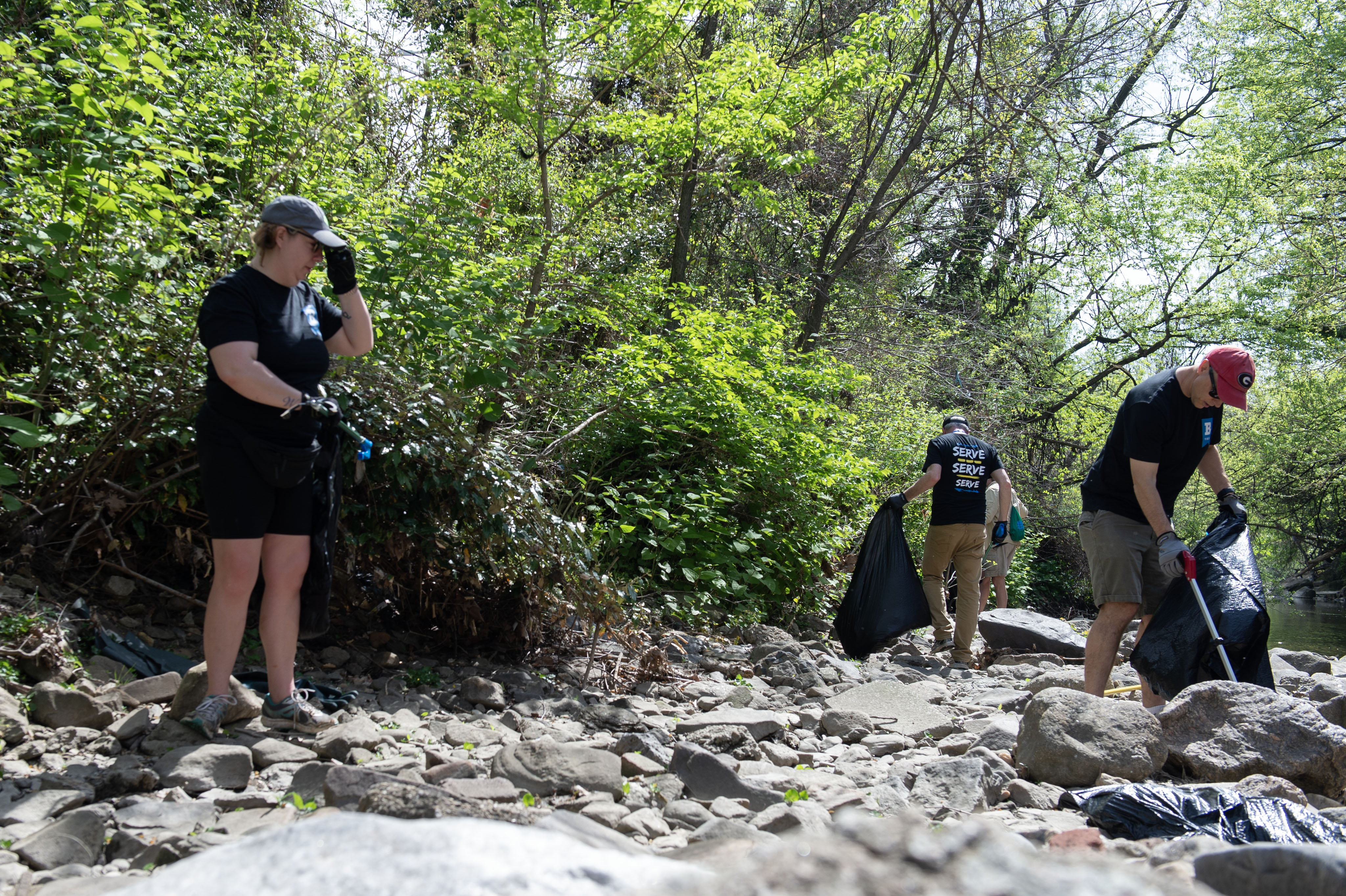 Volunteers clean up trash strewn alongside the Jones Falls creek.