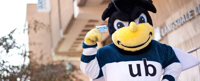 University of Baltimore Mascot Eubie holding a UBalt Bee Card