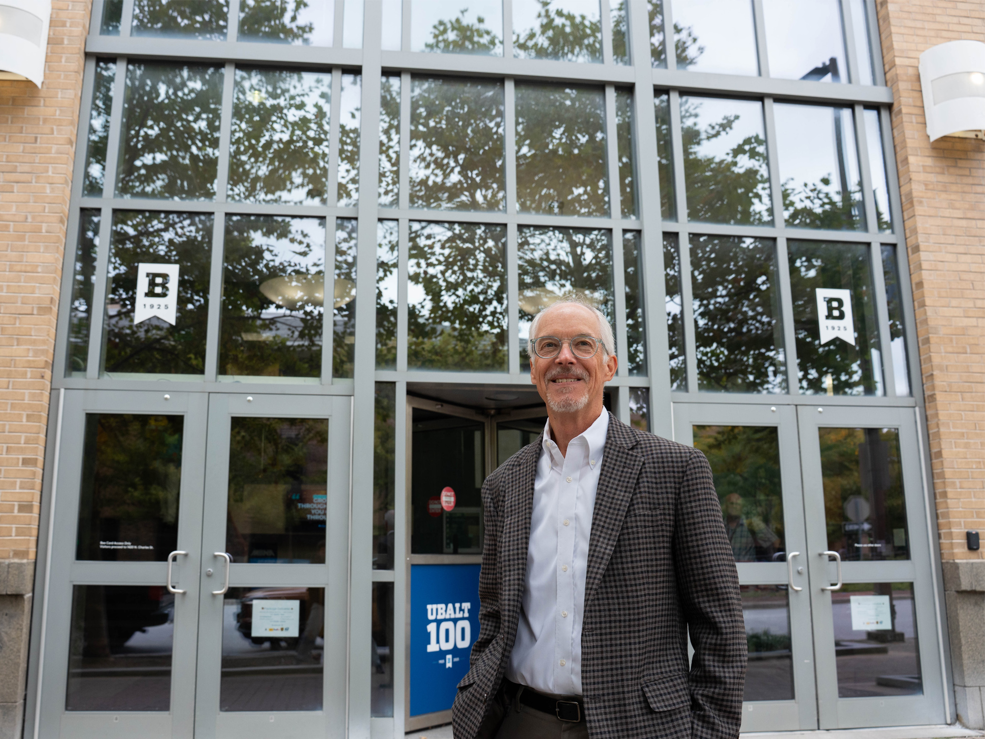 Associate Professor Bill Carter standing in front of the doors of University of Baltimore Business Center