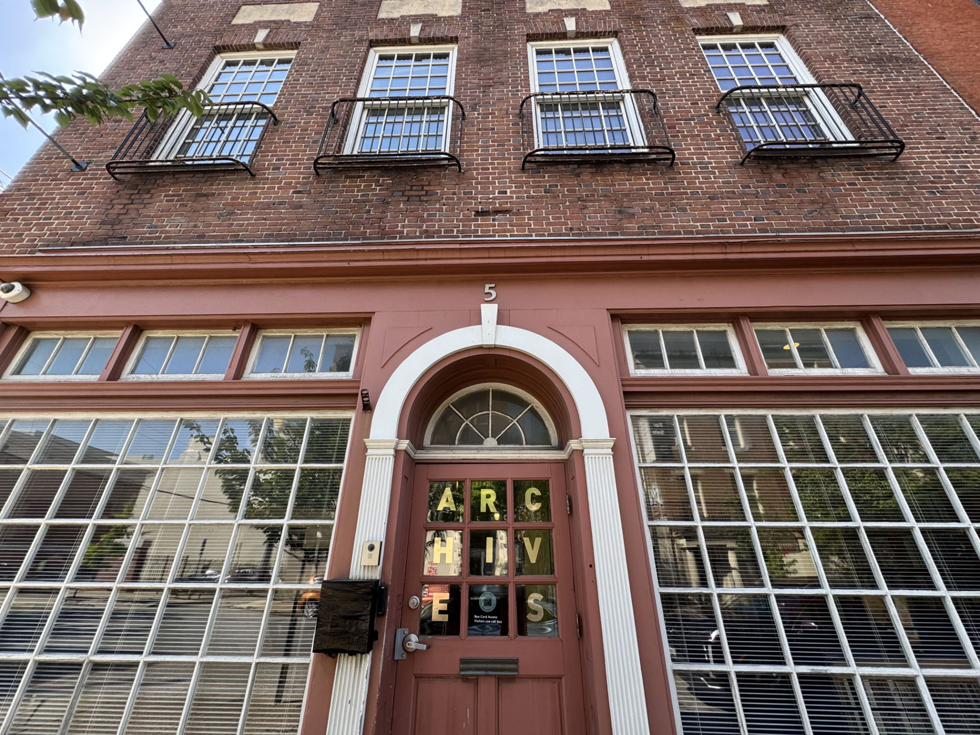 Exterior of the RLB Library Special Collections and Archives building at 5 Chaste Street in Baltimore, showing a red brick facade and arched entrance labeled “Archives.”