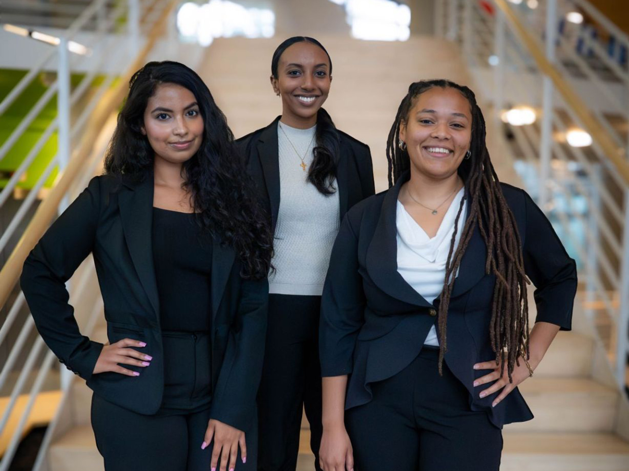 Three law students pose on the staris of the law center