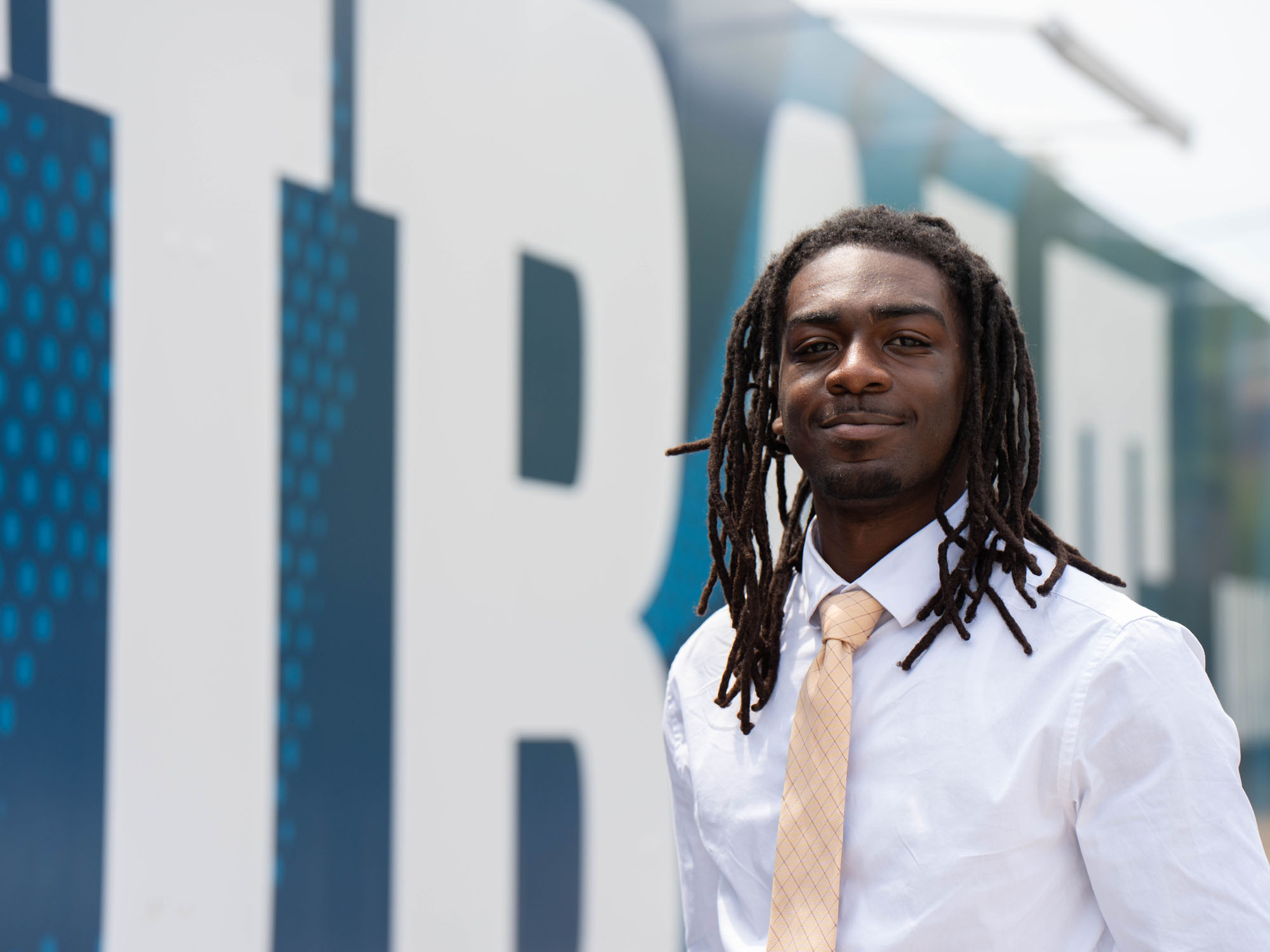 Student Kevin Morgan stands in front of UBalt's campus mural.