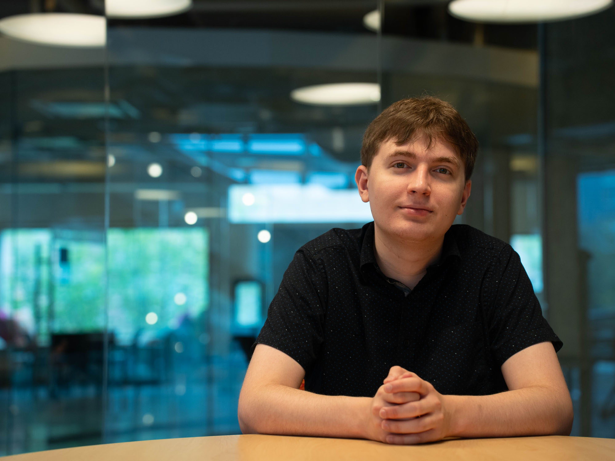 Nicholas Charalambous poses while sitting in the library
