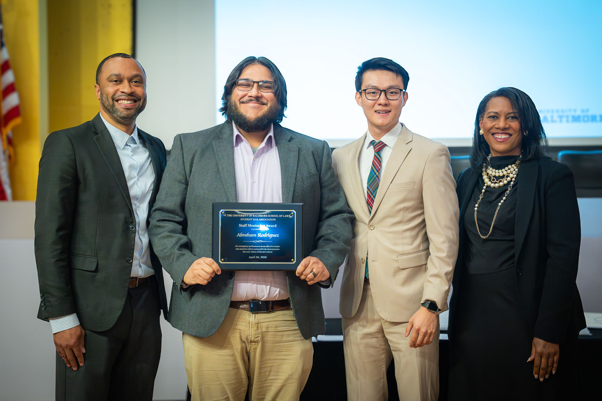 Four people pose during a University of Baltimore School of Law awards ceremony, with one recipient holding an award plaque.