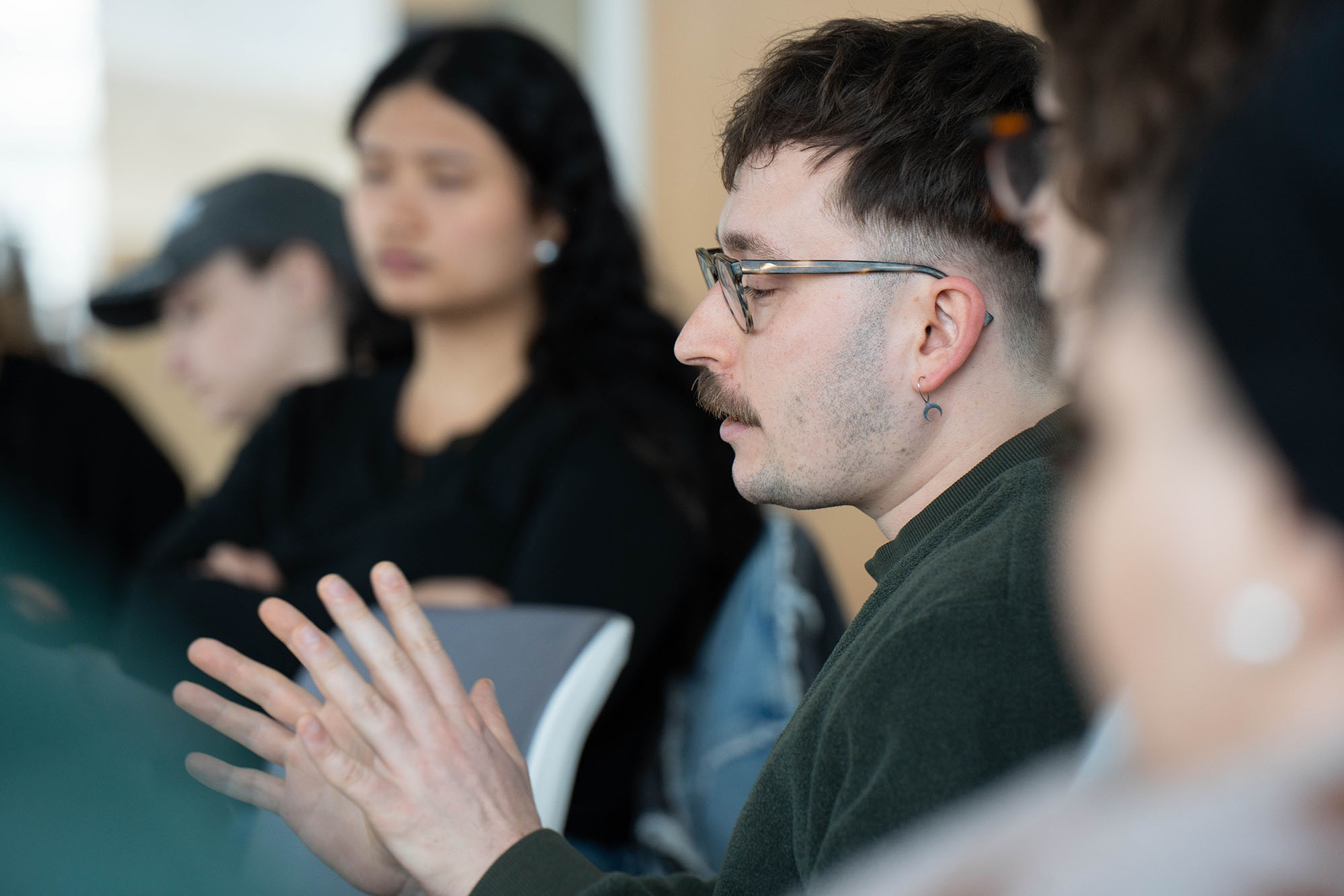 A male student uses his hands while speaking in a class.
