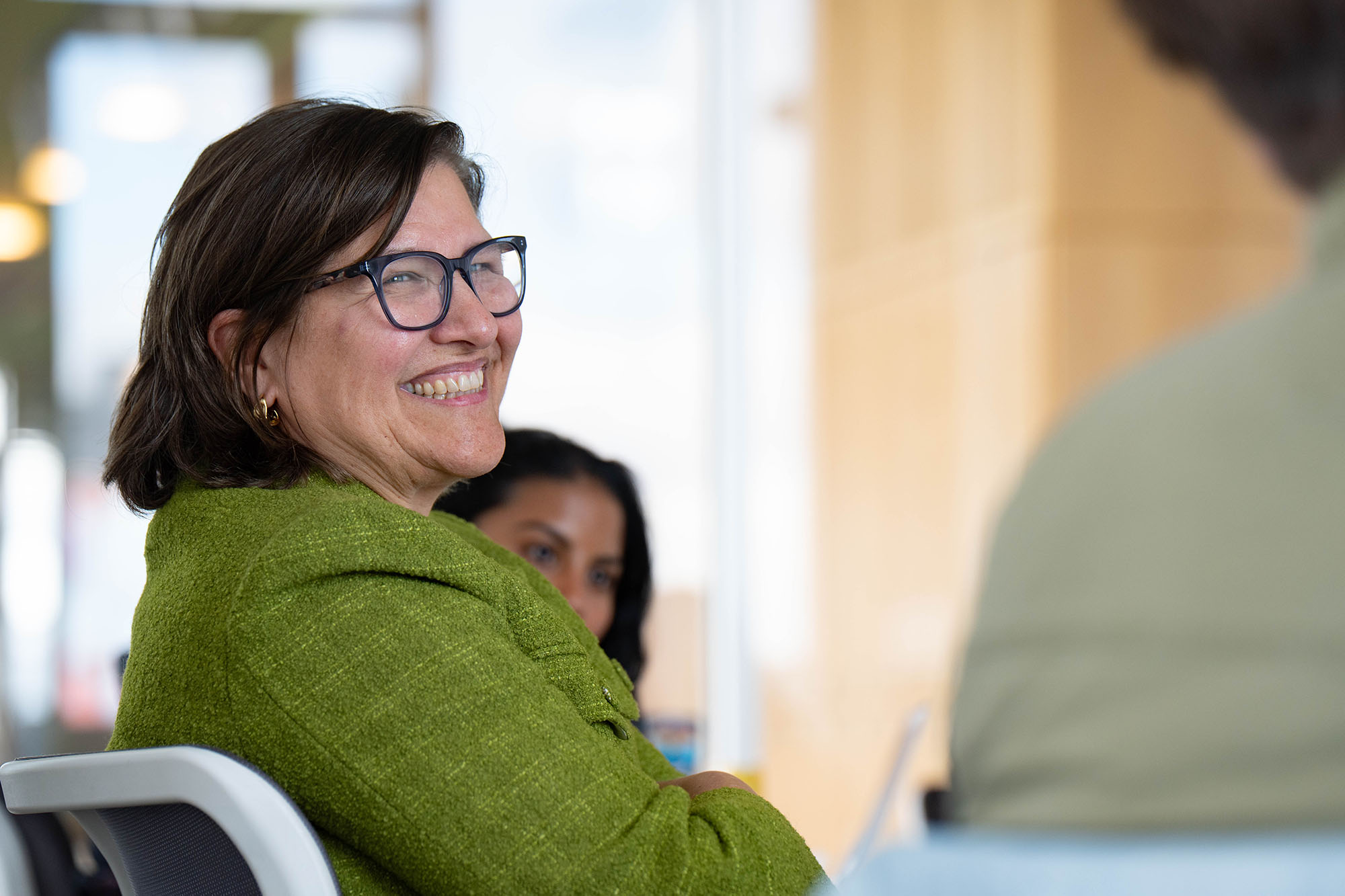 A professor smiles at a student during a class setting.