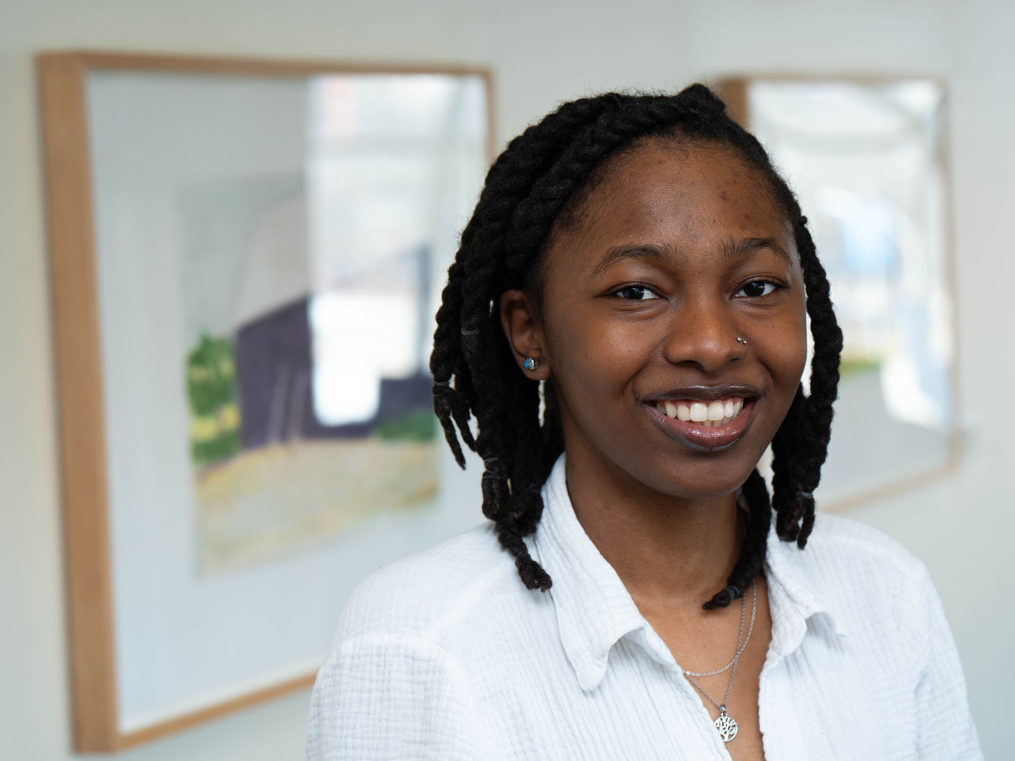 Bria Howard poses while standing in front of artwork in the hallway of the Student Center at UBalt.