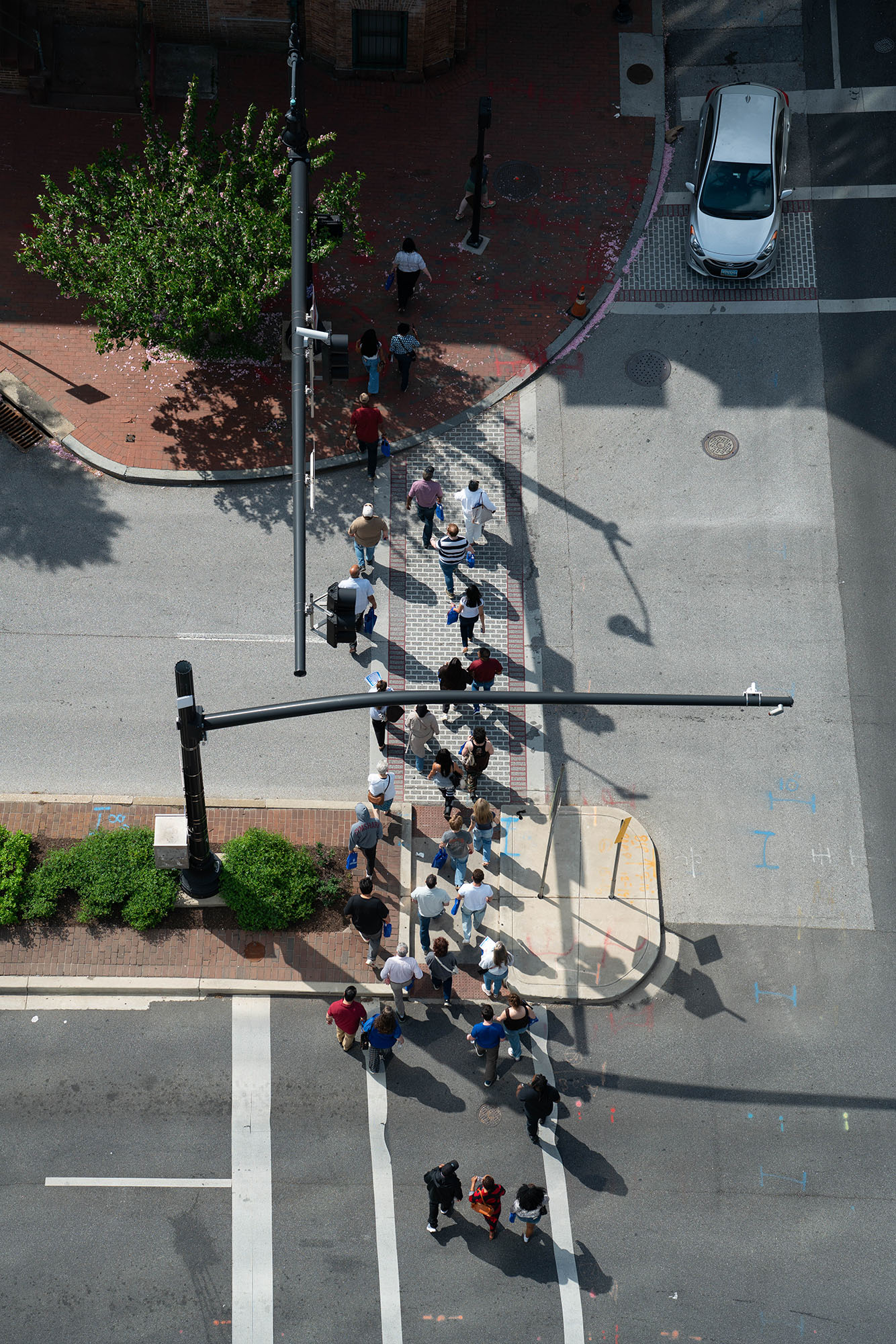 Seen from above, a group of people part of a University of Baltimore campus tour crosses the street. 