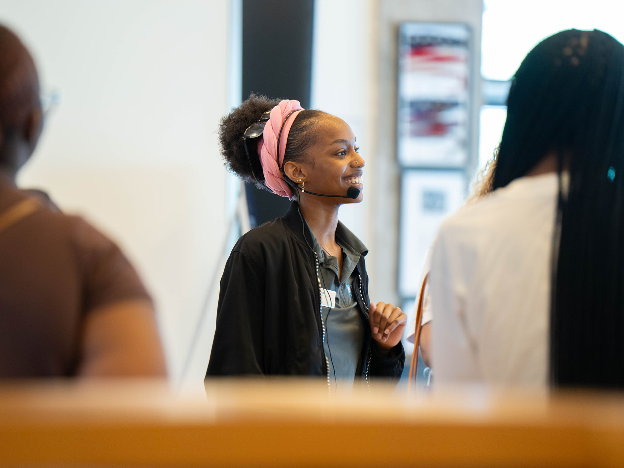 A student smiles while wearing a microphone and leading a campus tour.