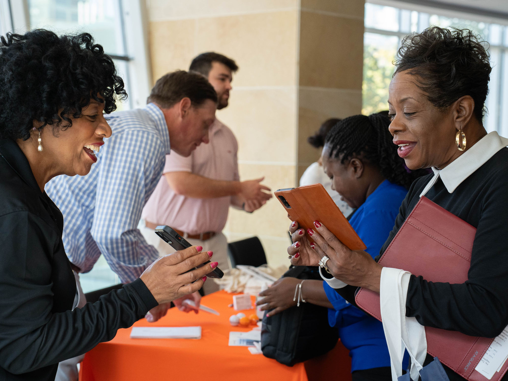 A student looks at her phone for reference while speaking with a visiting businesswoman during the career fair.