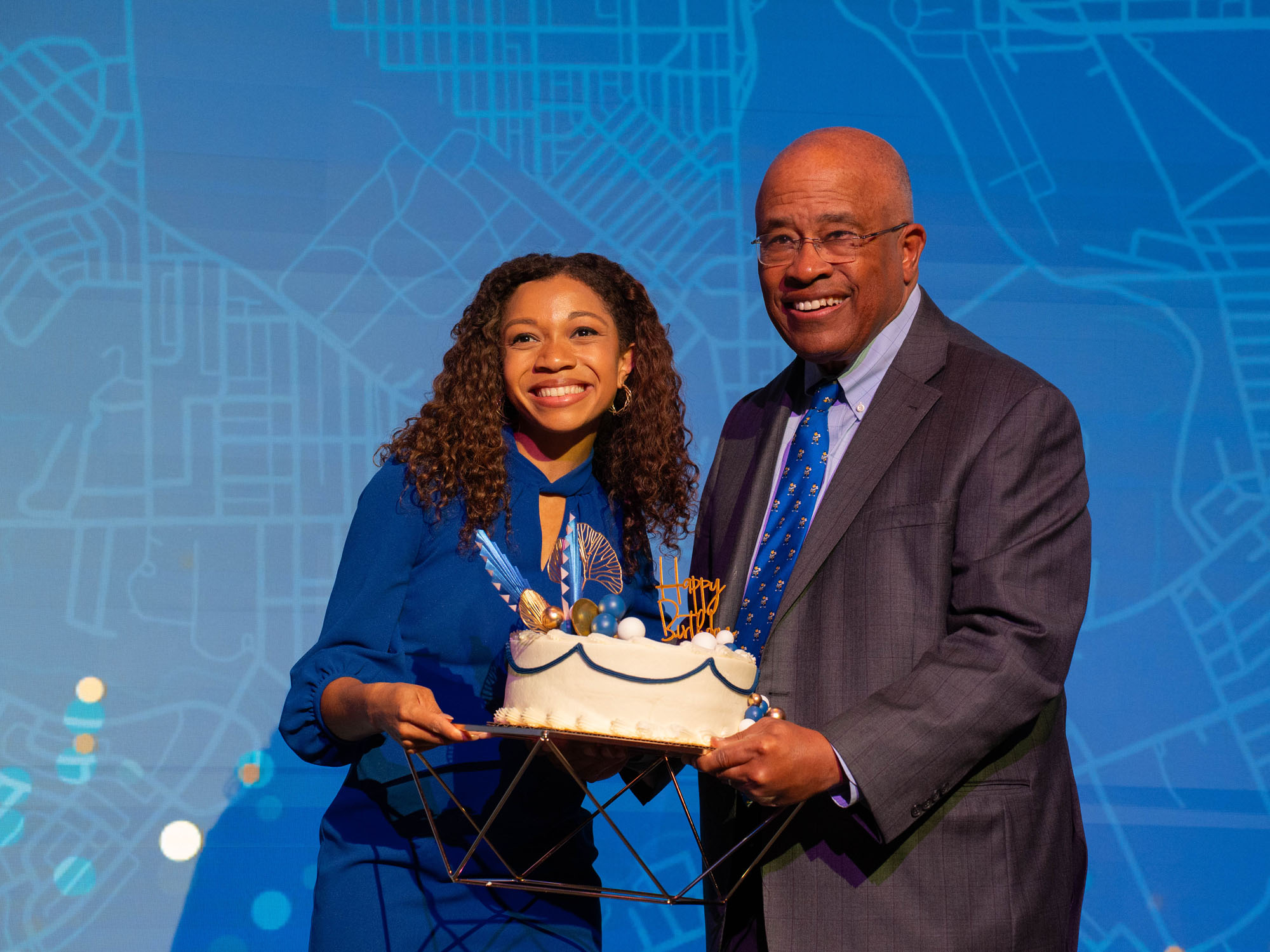 Kurt Schmoke and Breana Ross hold the cake for the Centennial. 