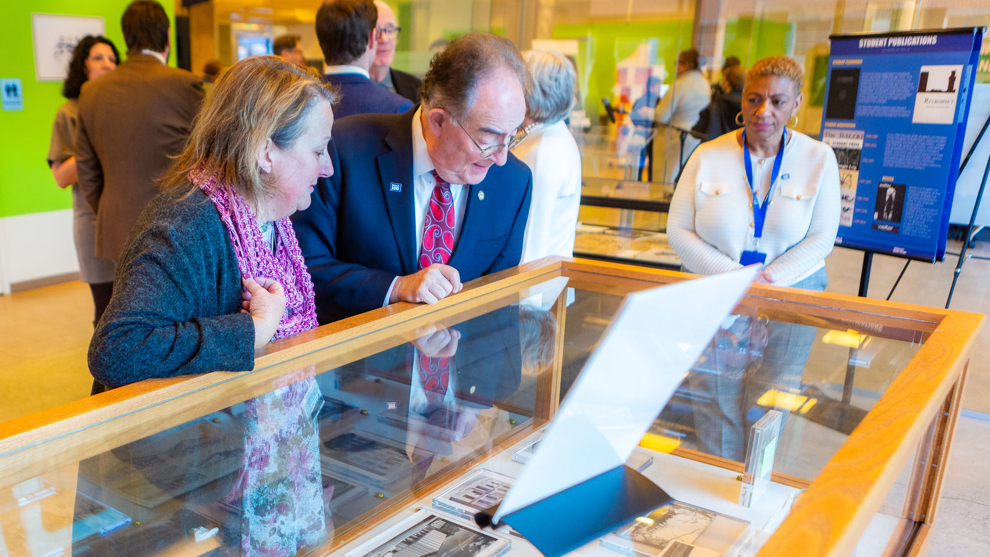 Cindy Schuster, an alum and staff member of UBalt, joins Jay Perman, chancellor of the University System of Maryland in observing the history exhibit on display during the Centennial Launch party.