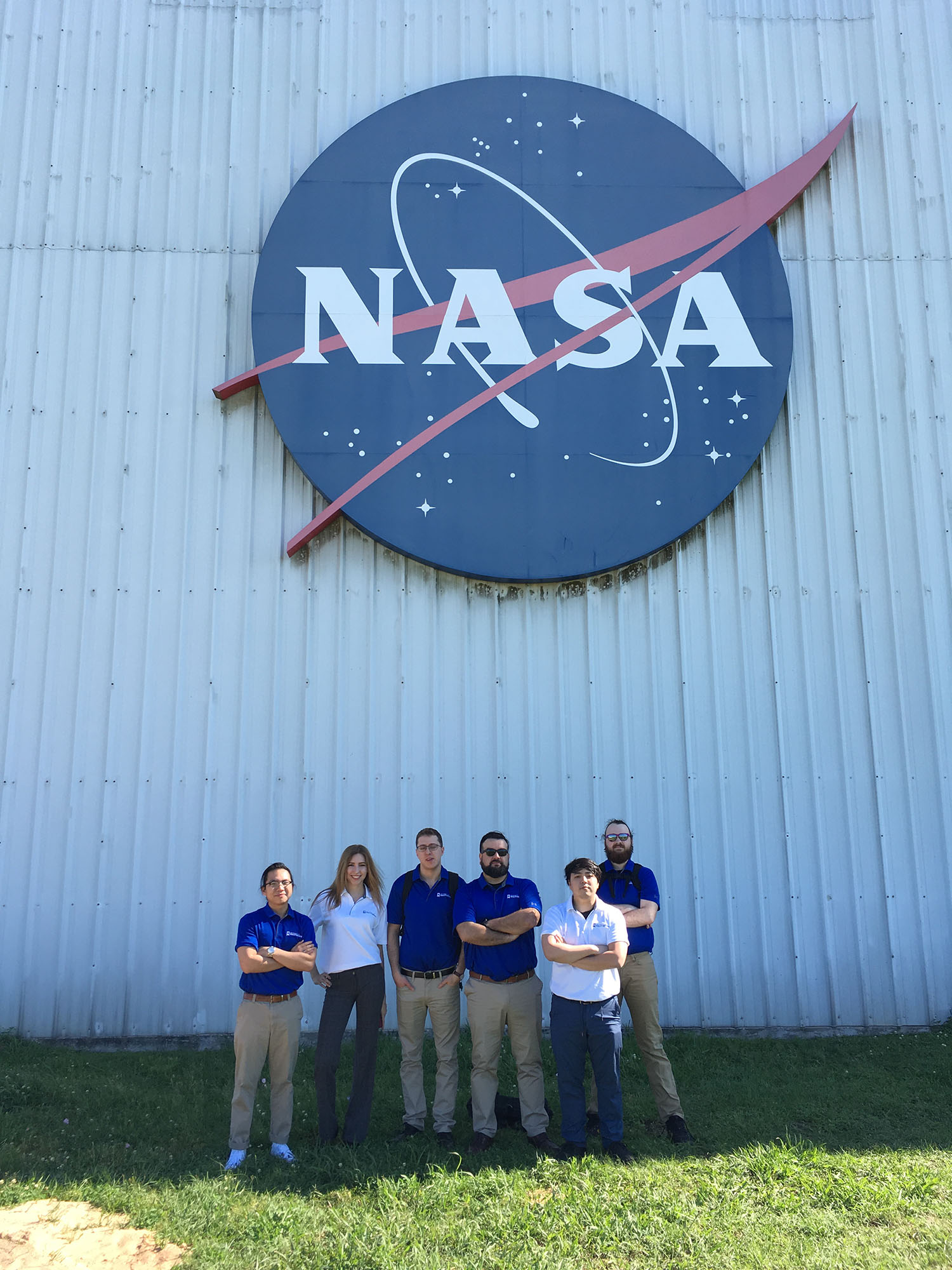 Students pose under the NASA logo during a visit.