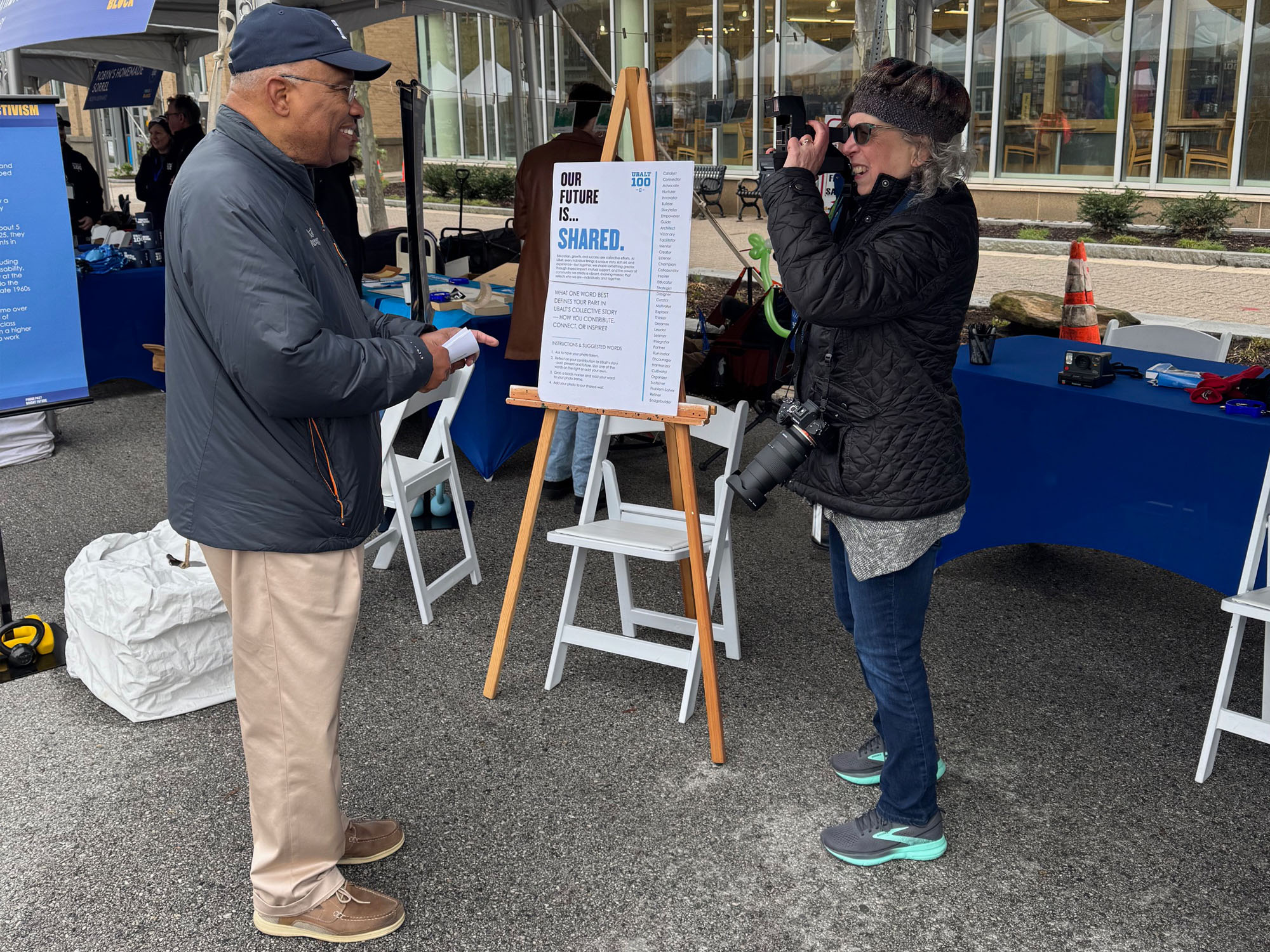 Julie Simon takes a photo of UBalt President Kurt Schmoke during the Centennial block party as part of one exhibit.