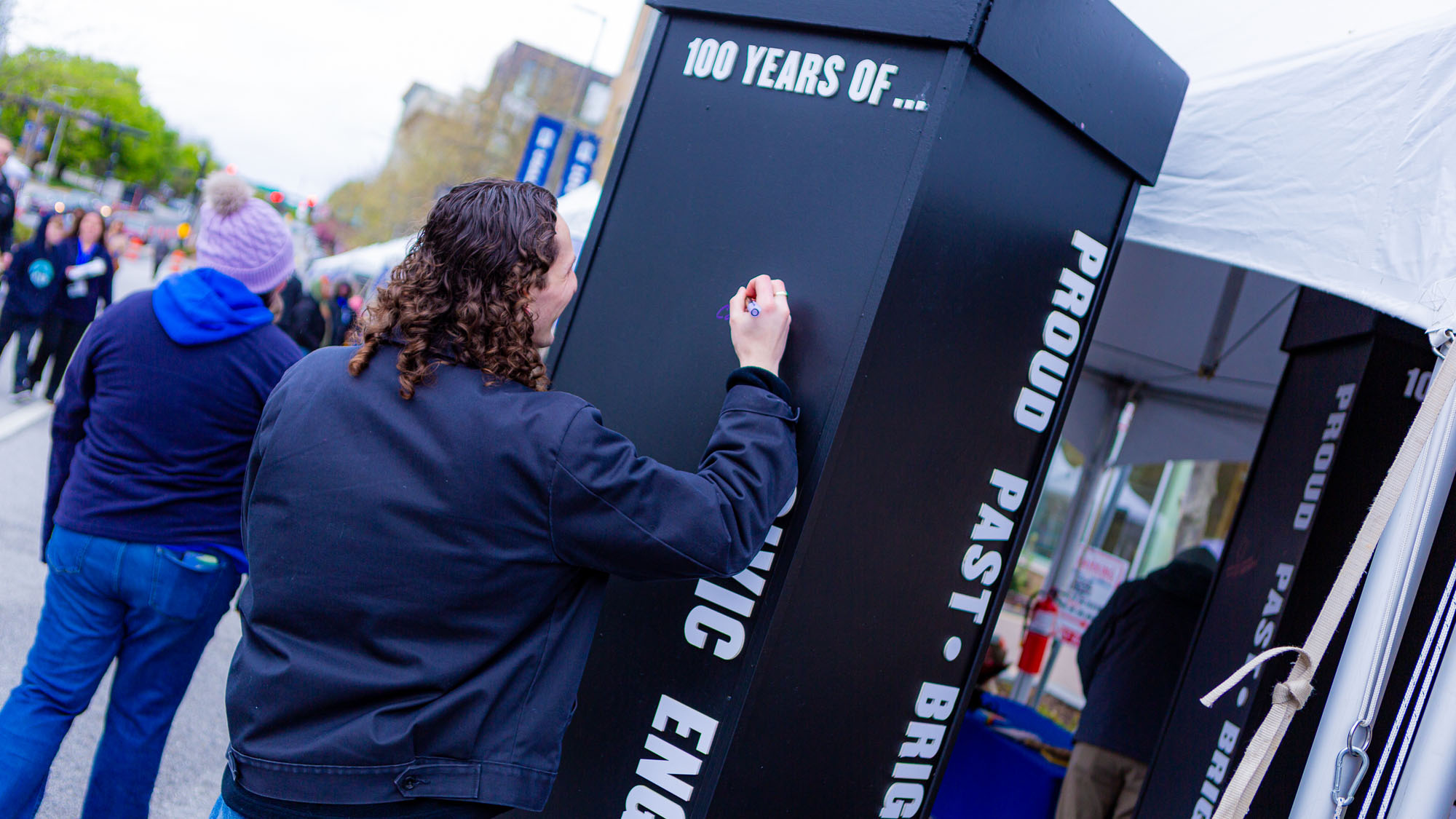 Jake Hicks, a graduate student who worked with professors Megan Rhee and Julie Simon on the Centennial exhibits, makes his mark on one of the exhibit pillars.