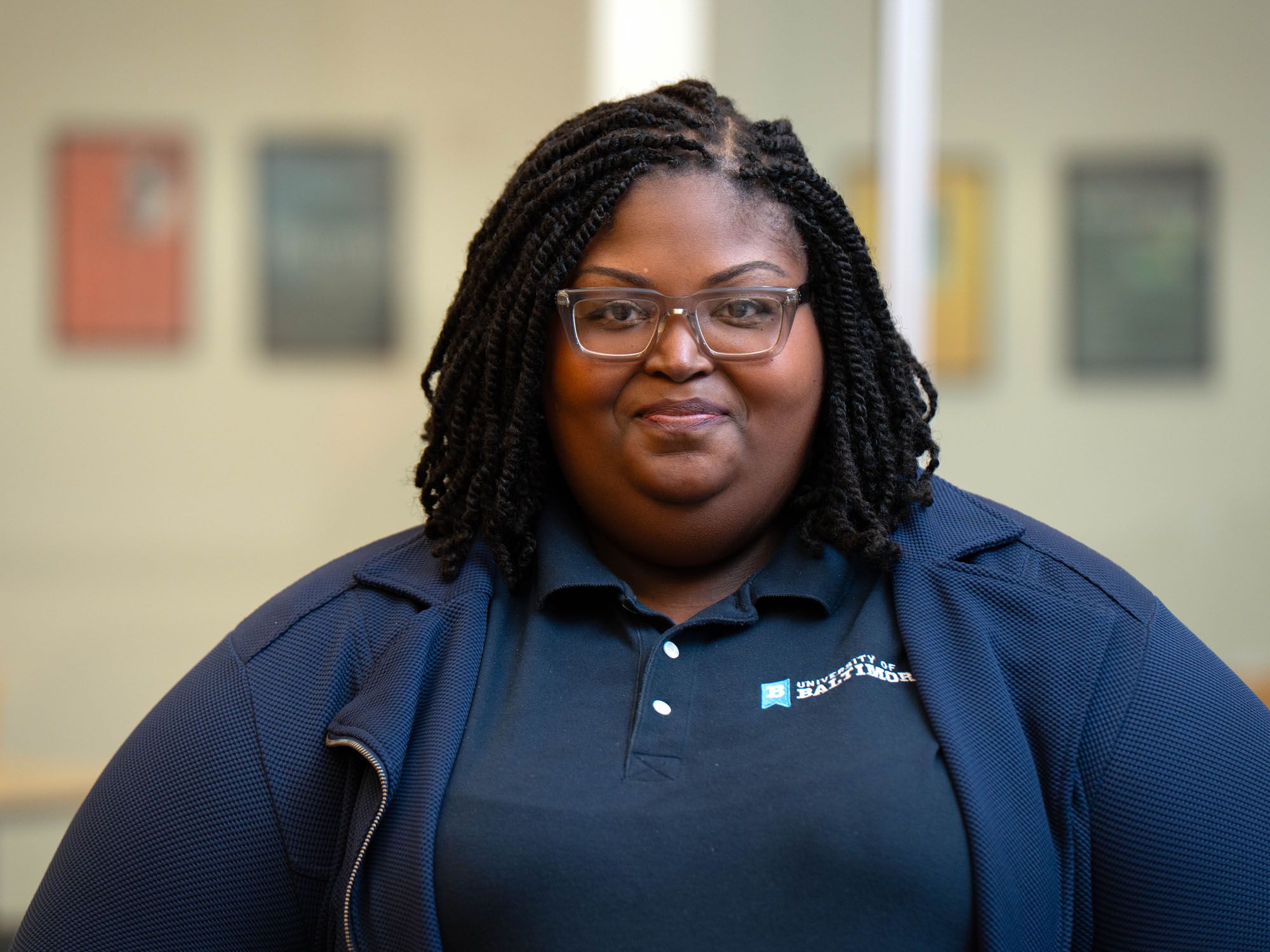 A student smiles at the camera in a portrait shoot in a campus classroom.