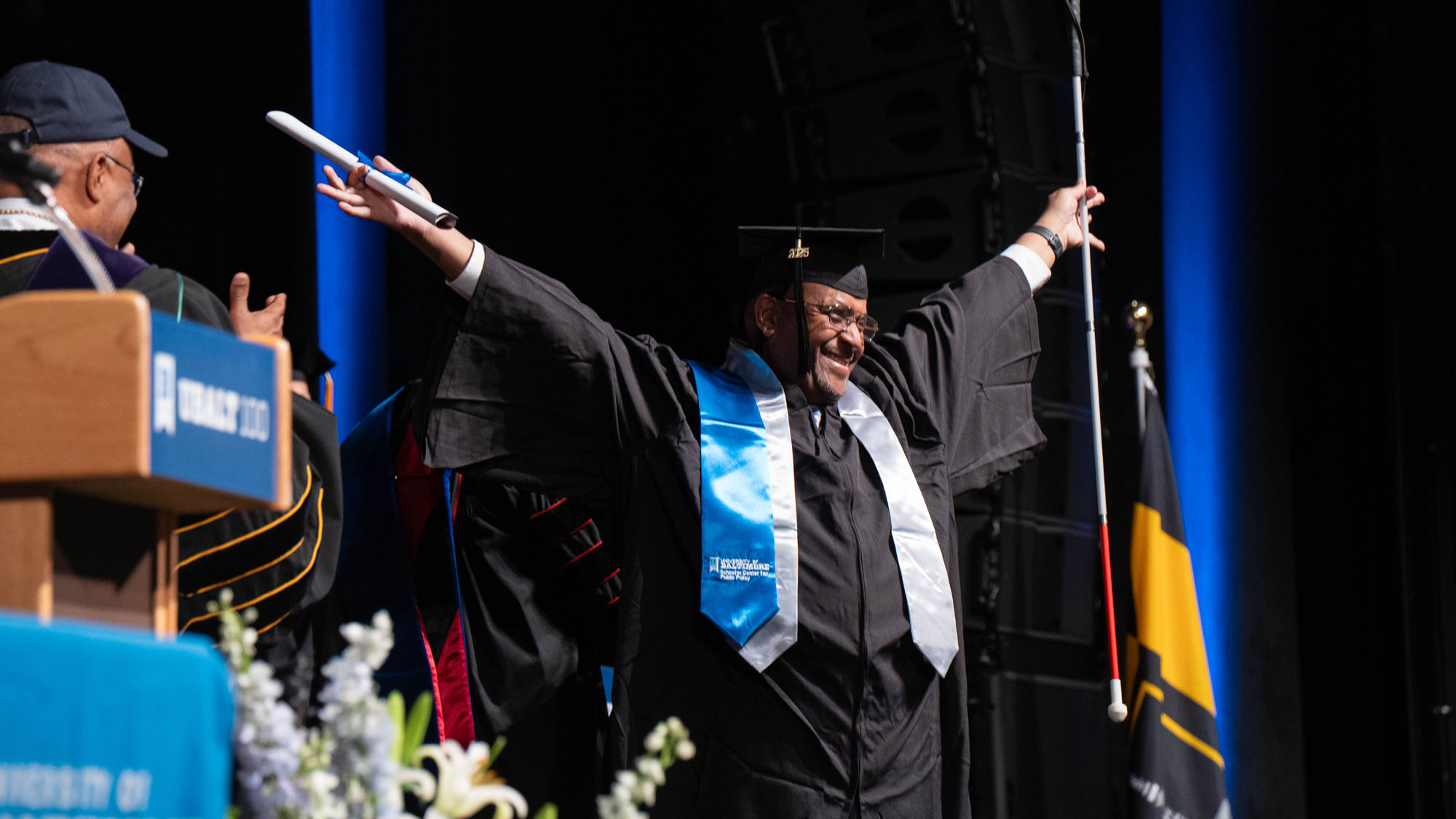 A student raises his arms in celebration as he graduates.