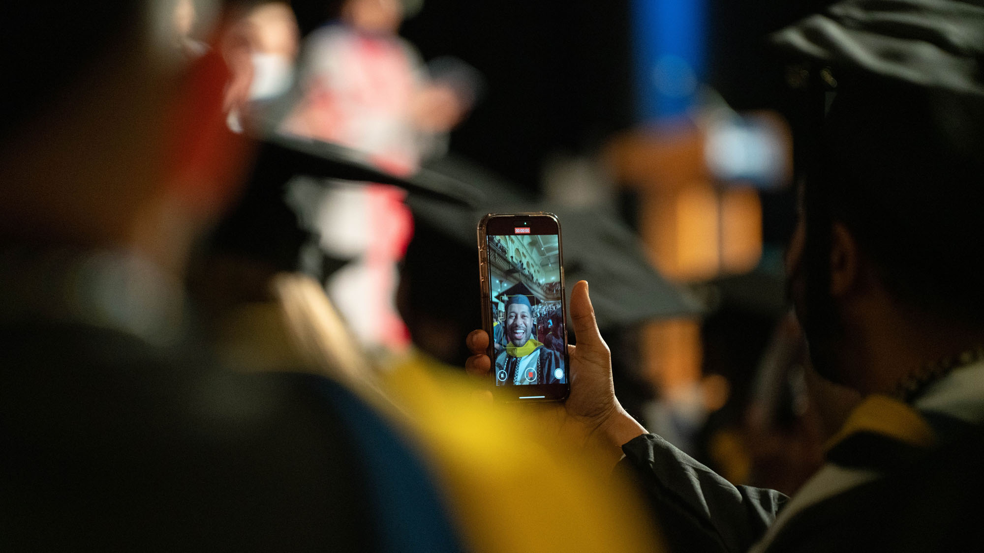A graduate records a video selfie during the commencement ceremony.