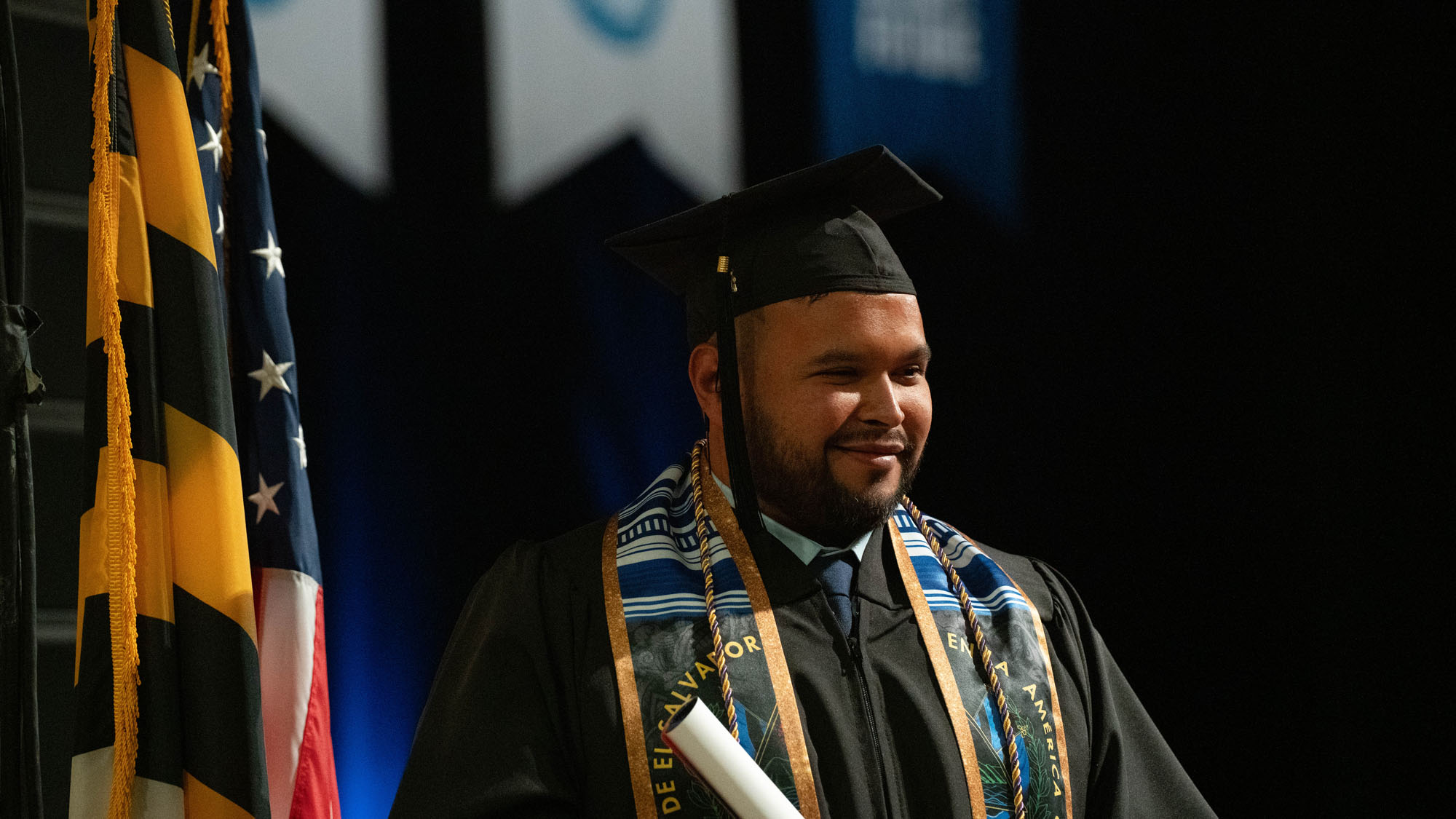 A graduate smiles from the stage.