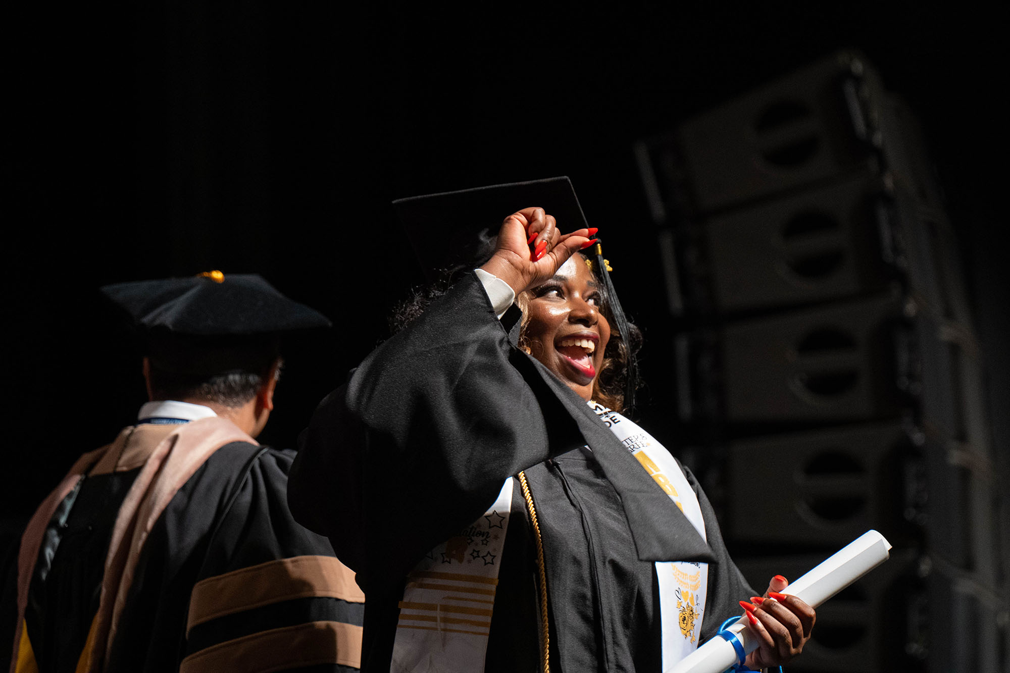 A graduate gestures to the audience after receiving her diploma.