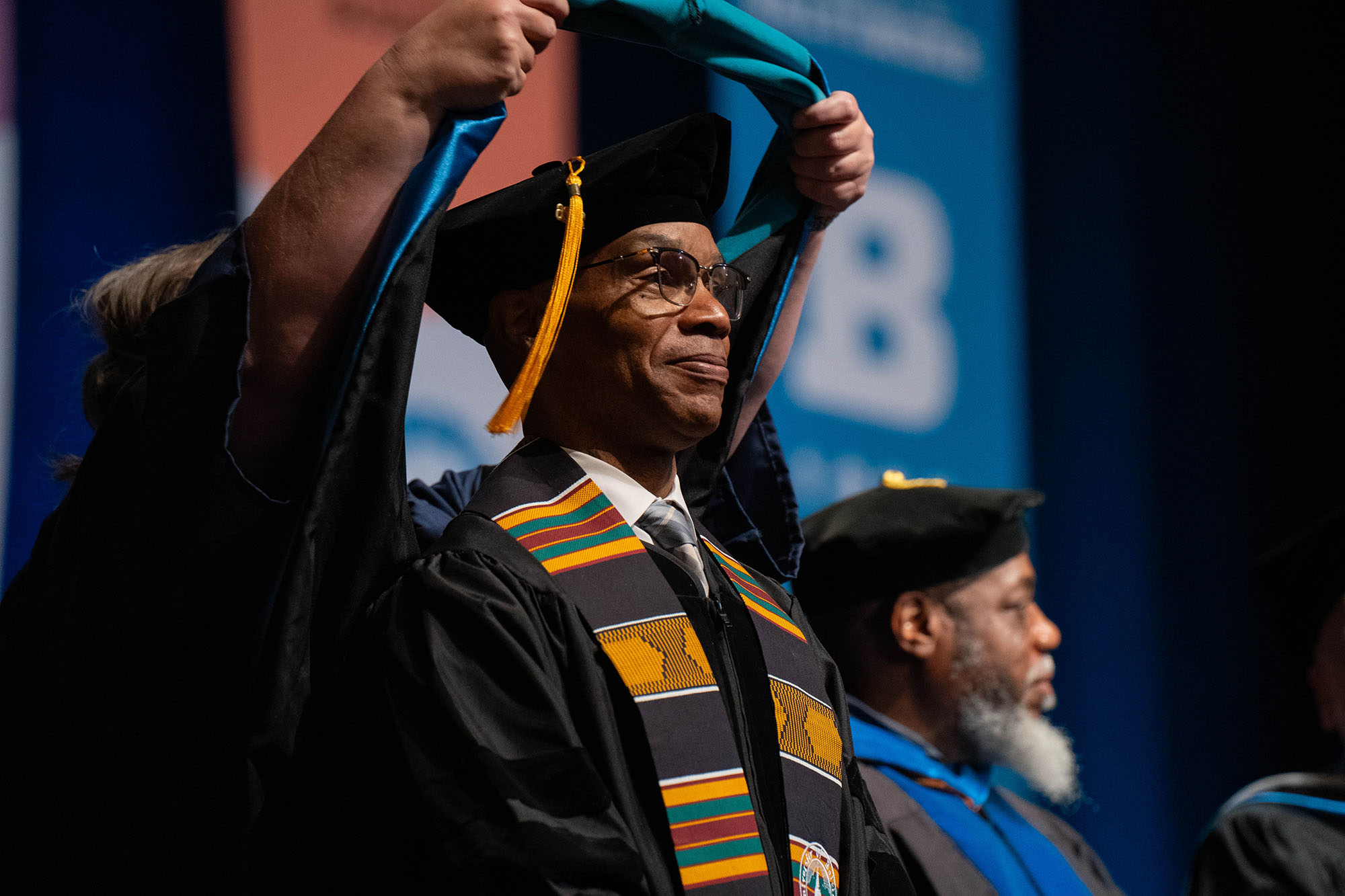 A graduate receives his hood during the commencement ceremony.