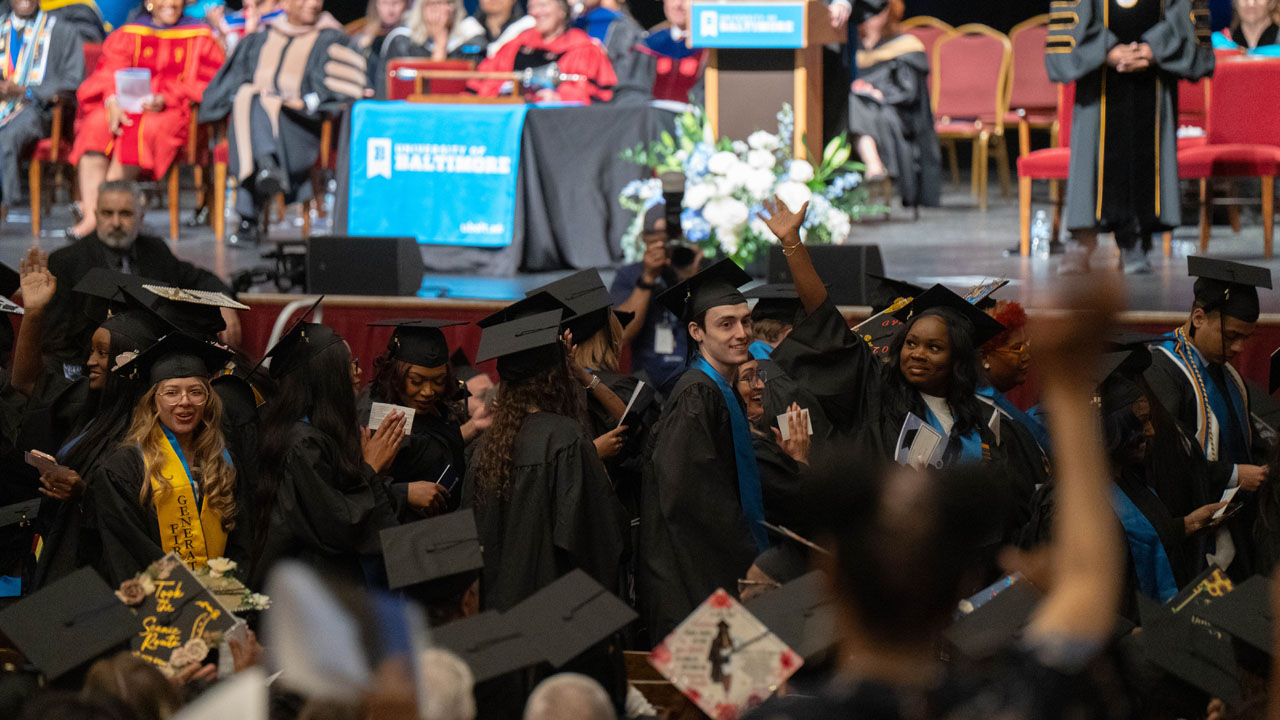 Graduates turn to wave to their loved ones at the start of The University of Baltimore's 2026 commencement.