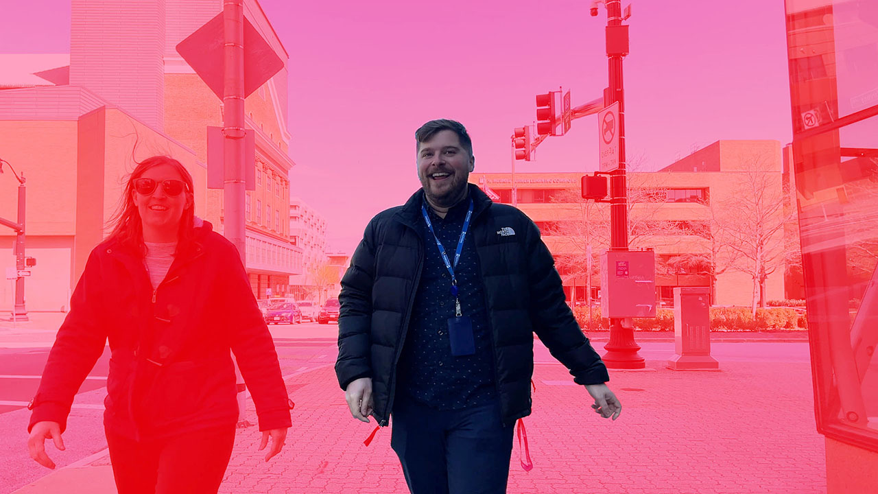 Matt Mazick, the adviser who is the subject of the video, walks down a city street, seen in a red splash from a graphic image