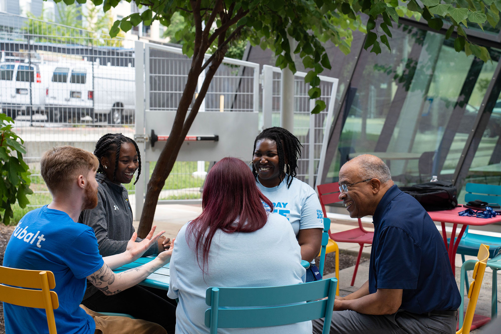 UBalt students sit around an outside table talking with the University President Kurt L. Schmoke.