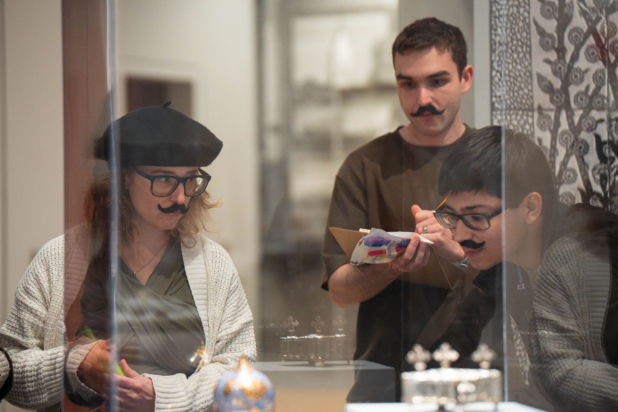 Students and their professor, all wearing fake mustaches, test an escape room.