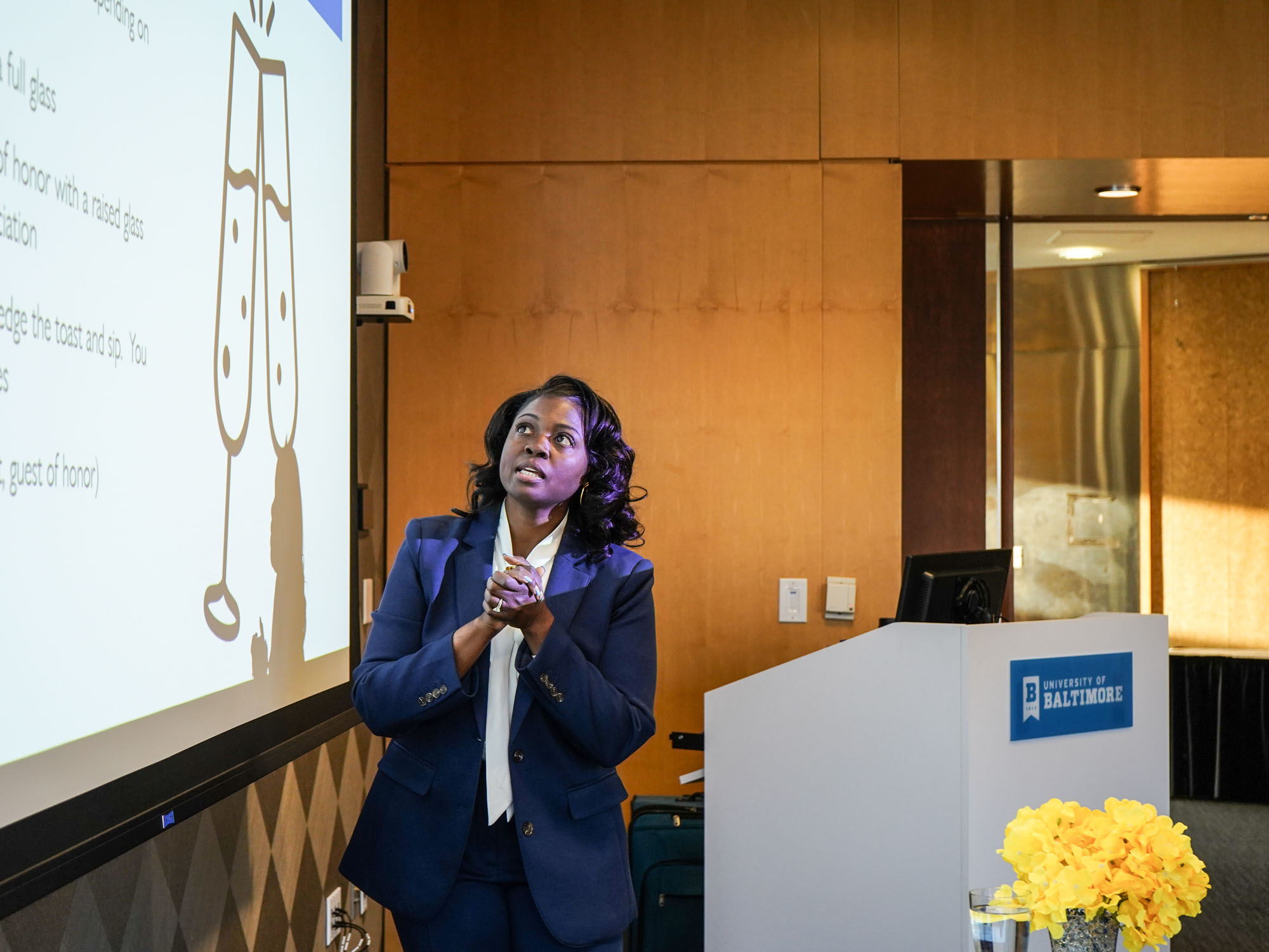 A woman gives a presentation while standing in front of a presentation.