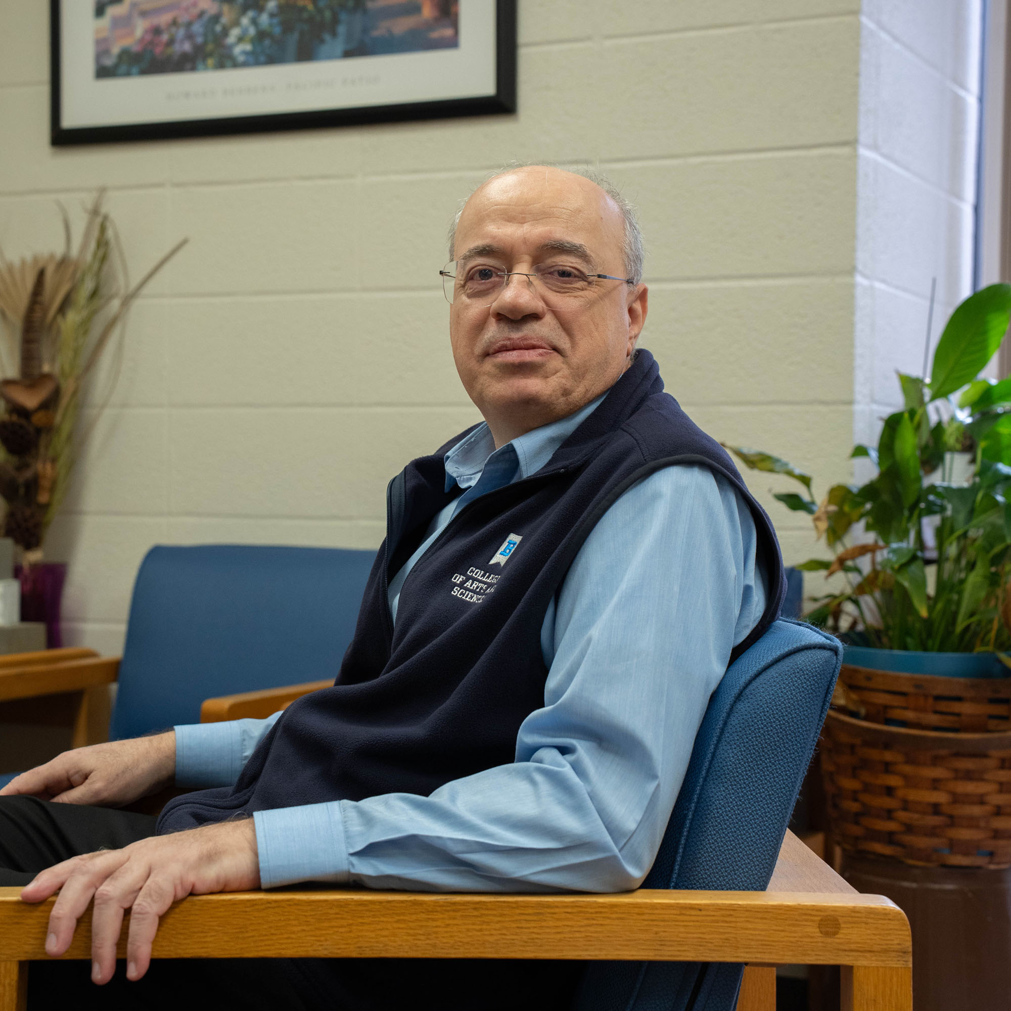 Haitham Alkhateeb smiles at the camera while posing in a chair inside an office suite where he works. 