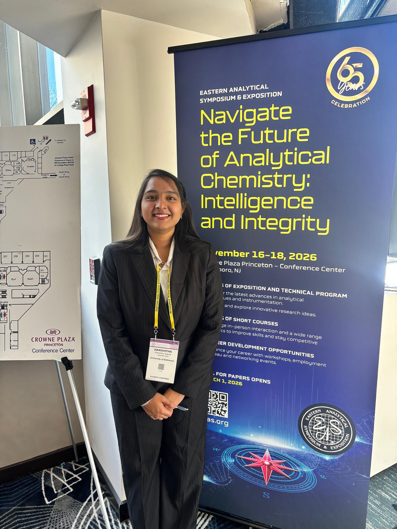 Harshitha poses next to a sign for the conference she was thrilled for a chance to attend and present at. 