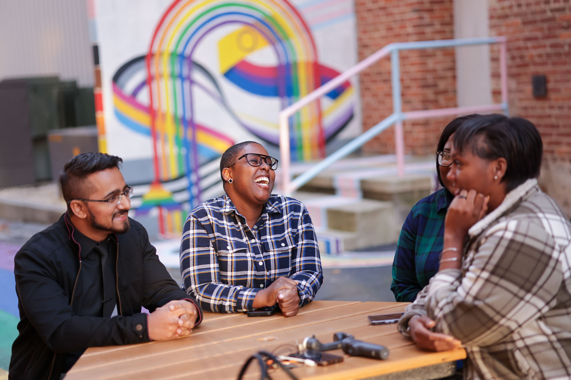 Students hang out at a table in the University of Baltimore's brightly colored mural-heavy Inclusion Alley, a celebration of love and the LGBTQIA+ community. 