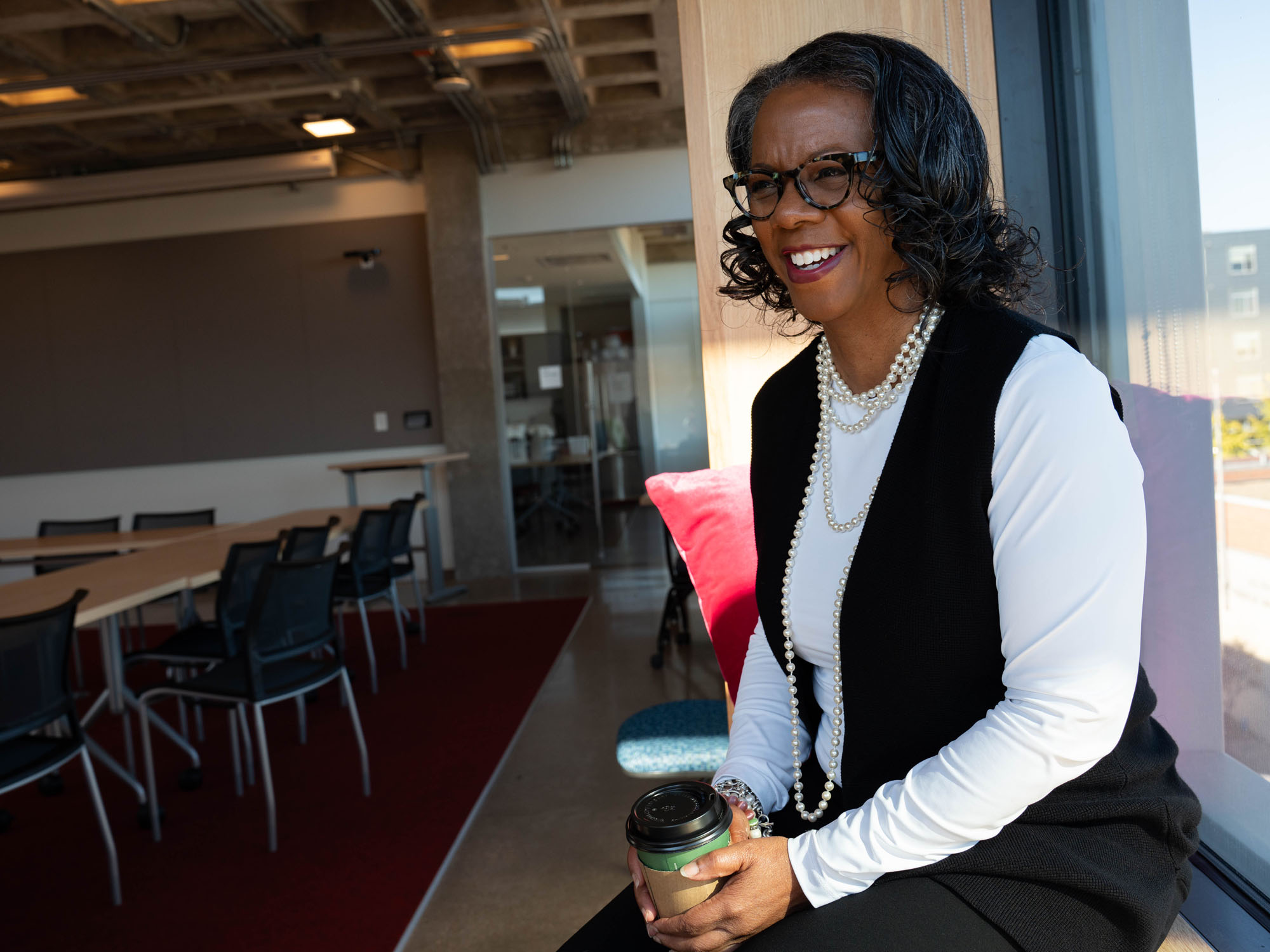 Jan Williams laughs during an interview while sitting in a window seat in the campus library.