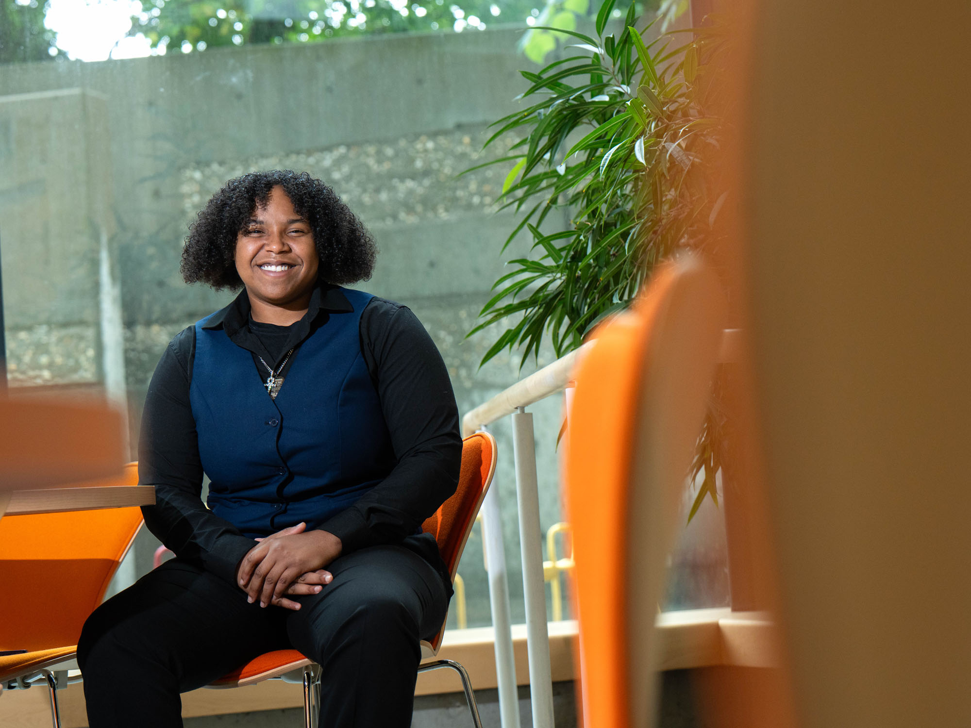 Jourdan Wallace sits in the atrium of the Law Center, framed around the orange chairs.
