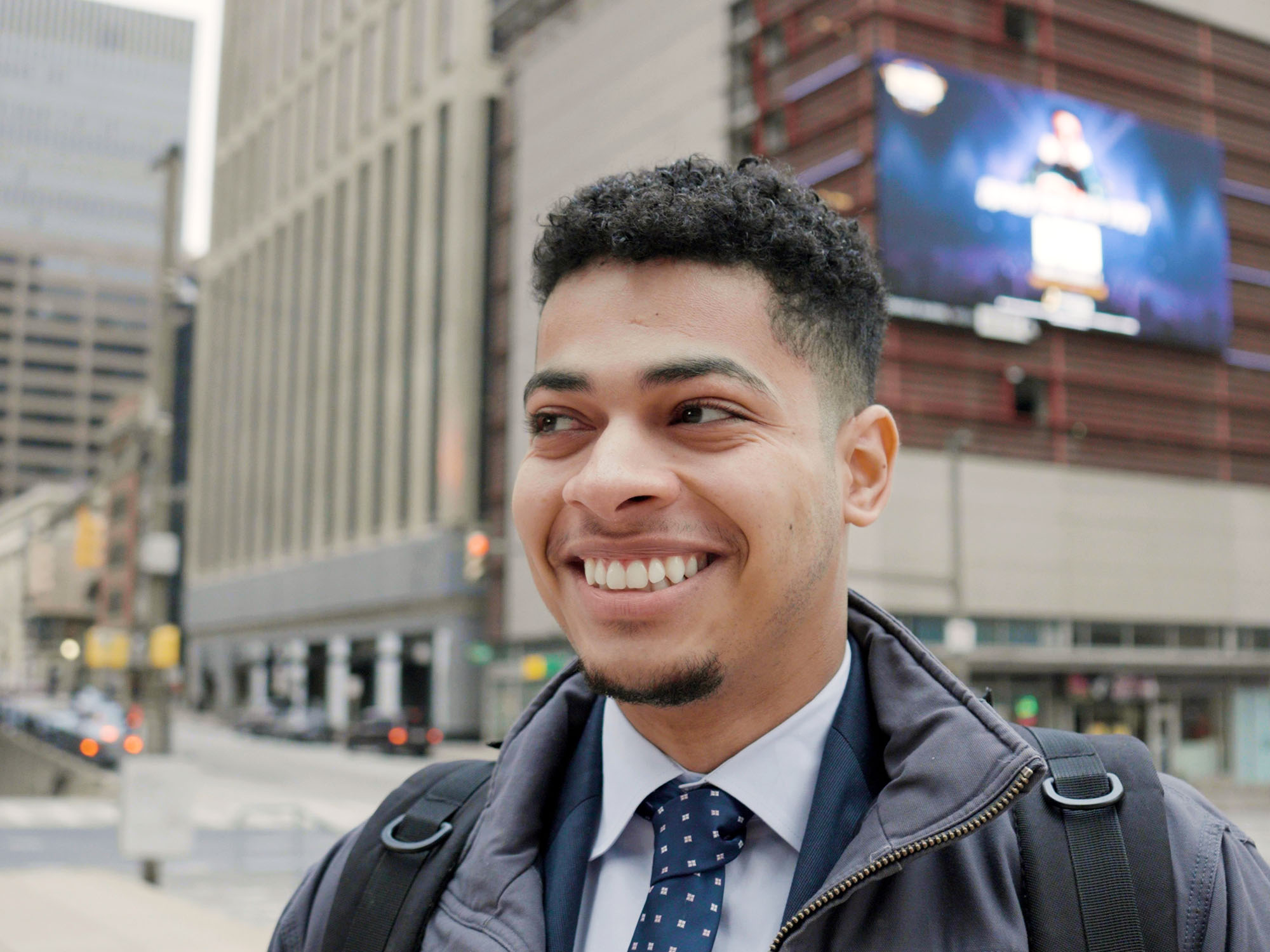 A student smiles while looking on and standing in the city of Baltimore.