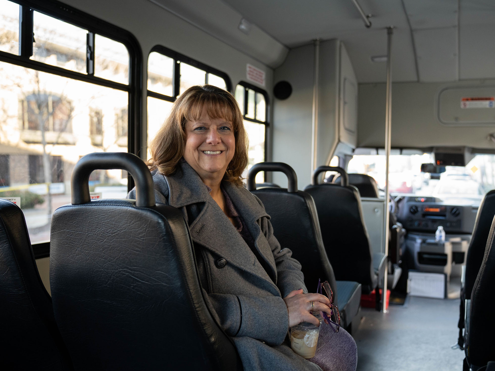 Karyn Schulz smiles while sitting on a bus 
