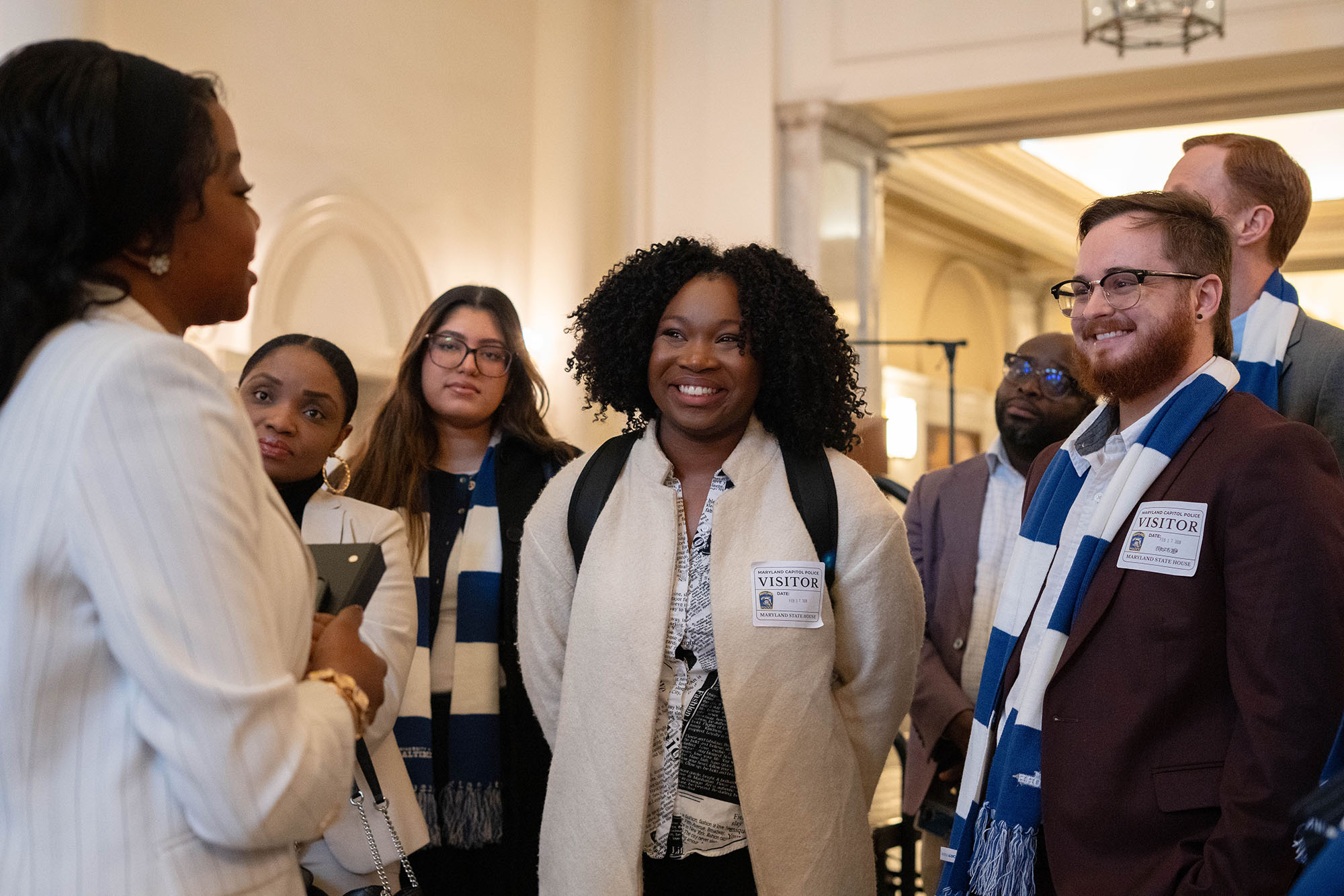 A group smiles while listening during a tour of the Maryland State House.