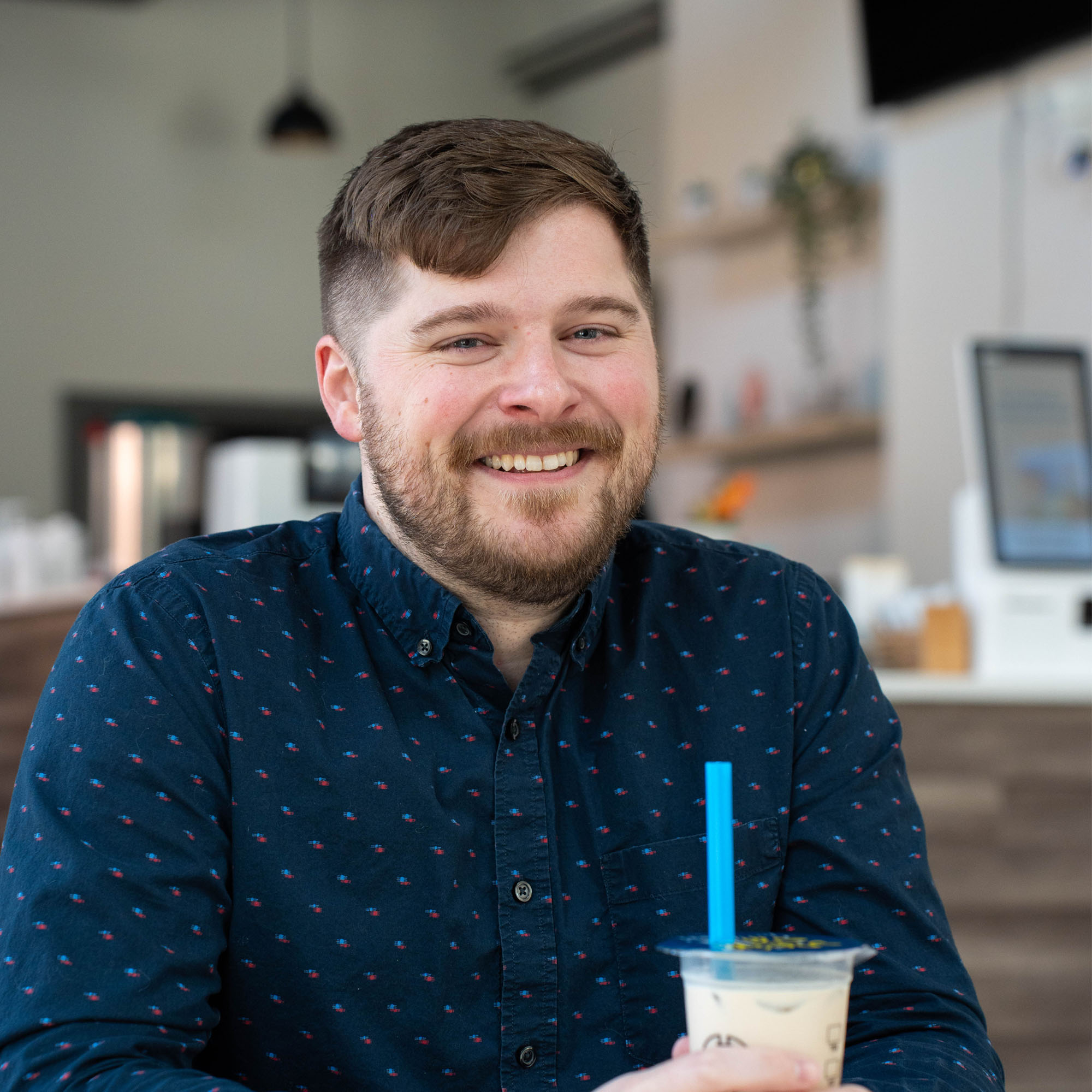 Matt Mazick, an adviser, poses in a cafe while holding a tea