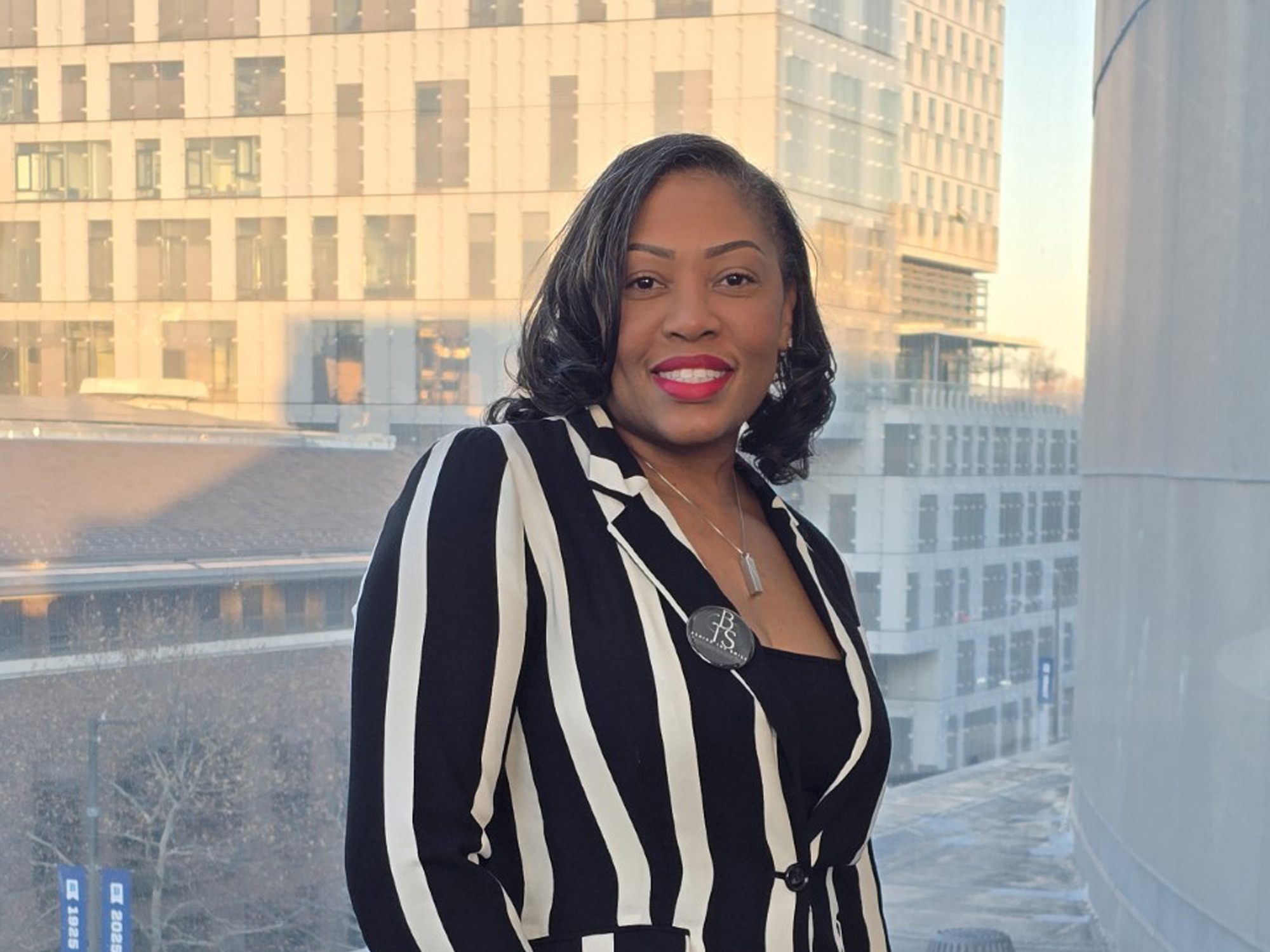 Mellanie Lee poses while standing in front of a window overlooking the city campus. 