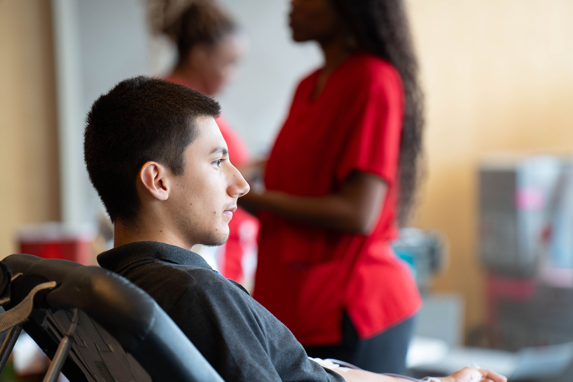 A student looks on while giving blood.