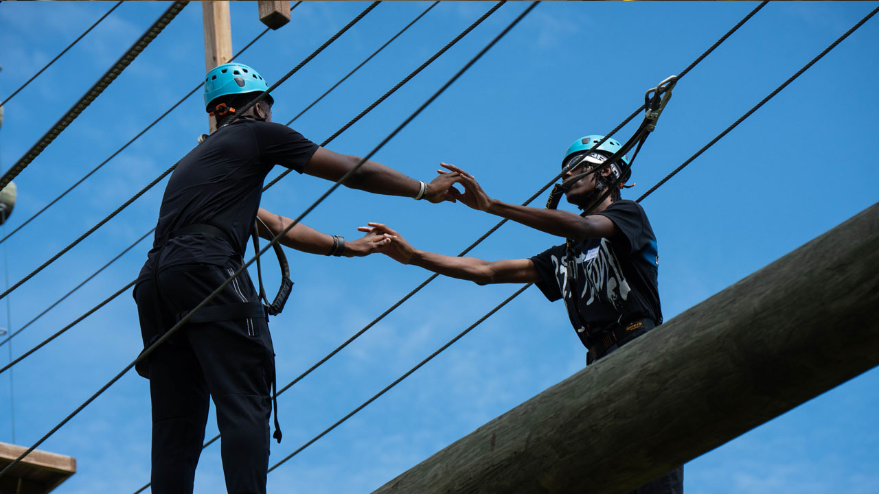 Two students steady each other on a ropes course.