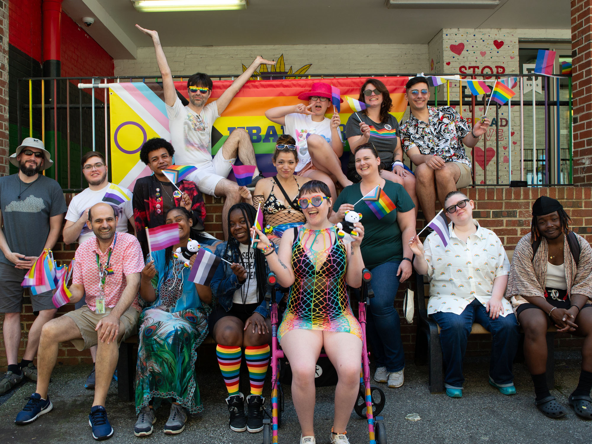 A group poses, smiling, for a photo during a Pride Month event at The University of Baltimore. Many hold or wave small flags representing different groups in the LGBTIA+ community. 