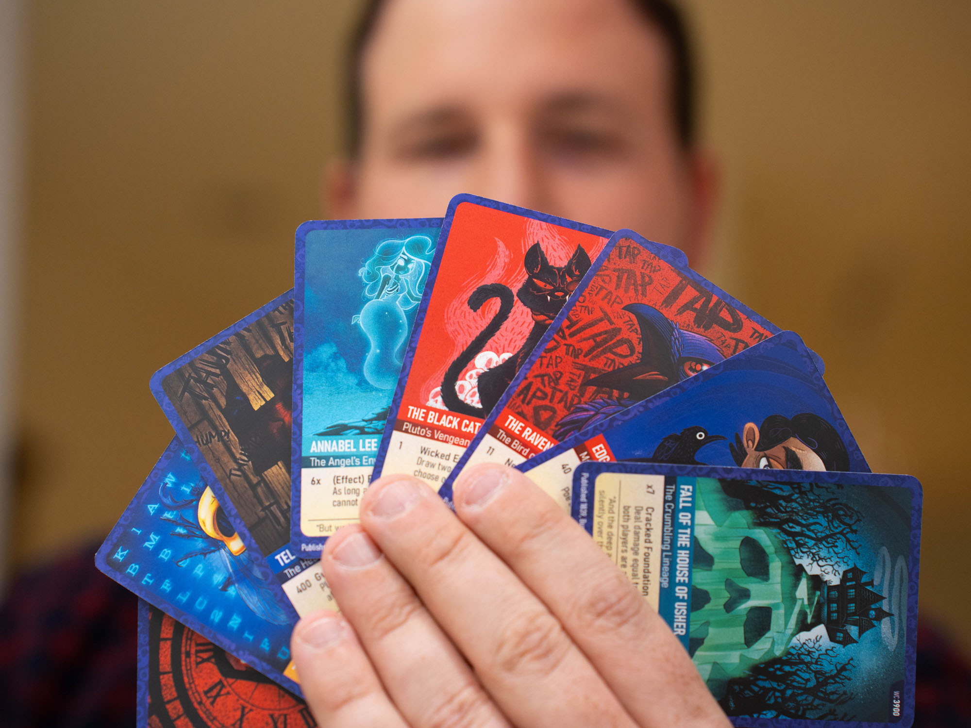 Sean Maykrantz holds an array of trading cards he designed, inspired by Edgar Allan Poe