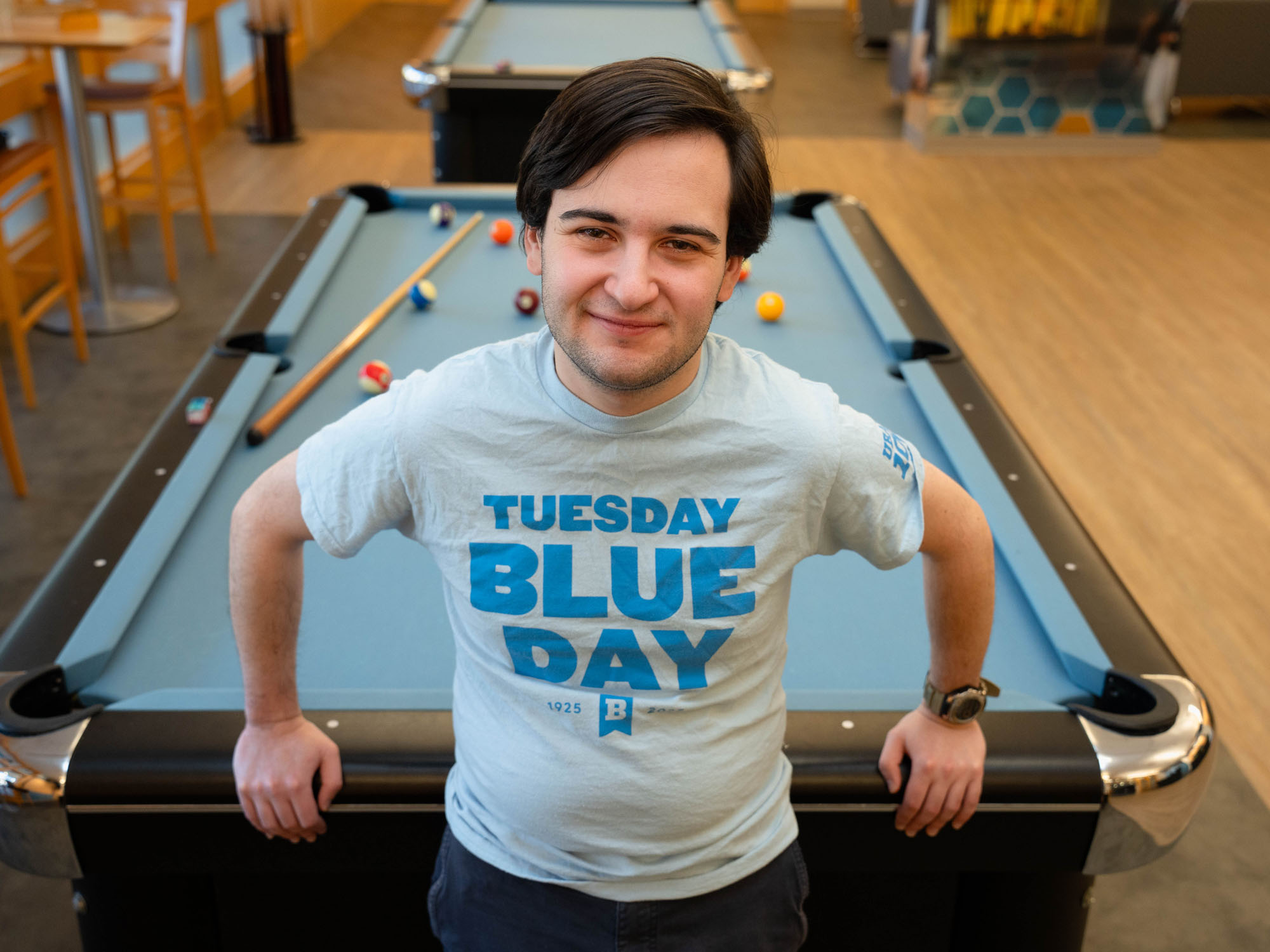 Seth, a UBalt student, leans against a pool table while posing for a photo.