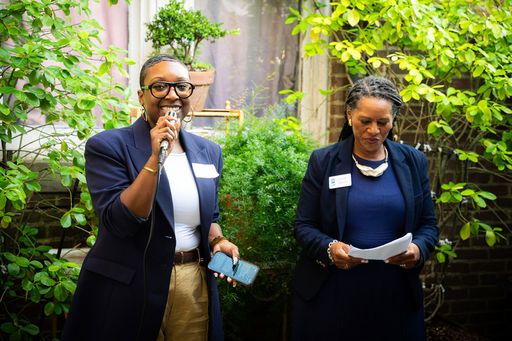 Two UBalt Law community members speak to attendees during an outdoor alumni event.