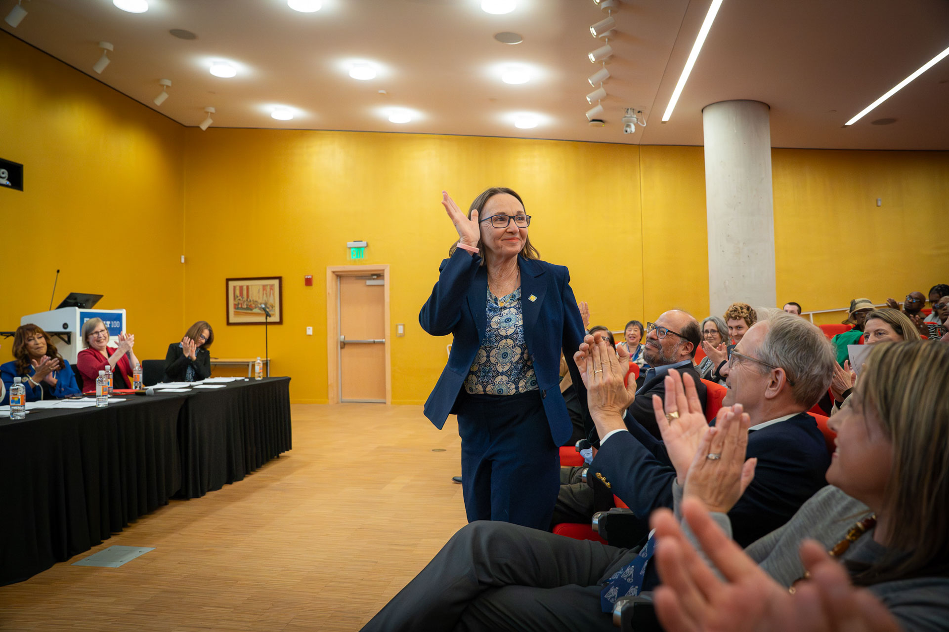 A person walks through an audience while receiving recognition at a University of Baltimore School of Law awards ceremony as attendees applaud.
