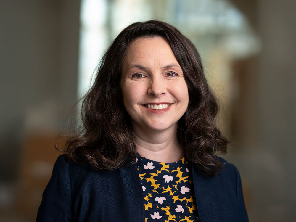 A professional headshot of a faculty member smiling and facing the camera.