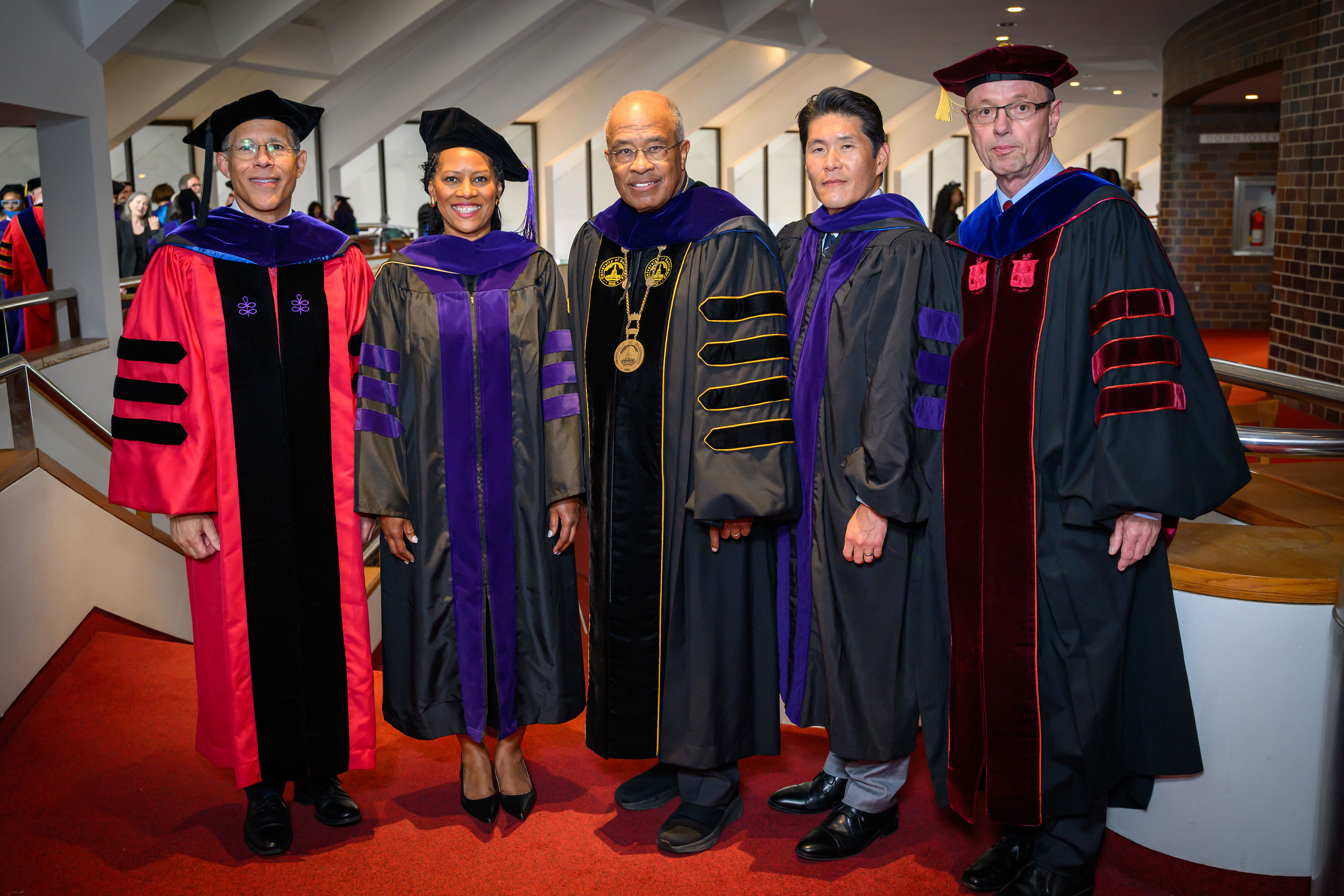 Five people in academic regalia pose together during the University of Baltimore School of Law commencement ceremony.