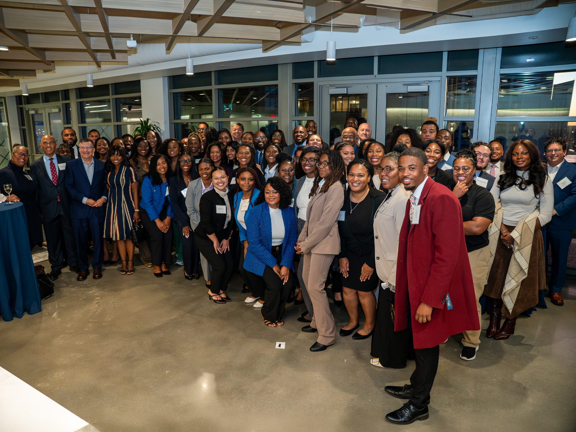 A large group of UBalt Law community members poses together at an indoor reception.
